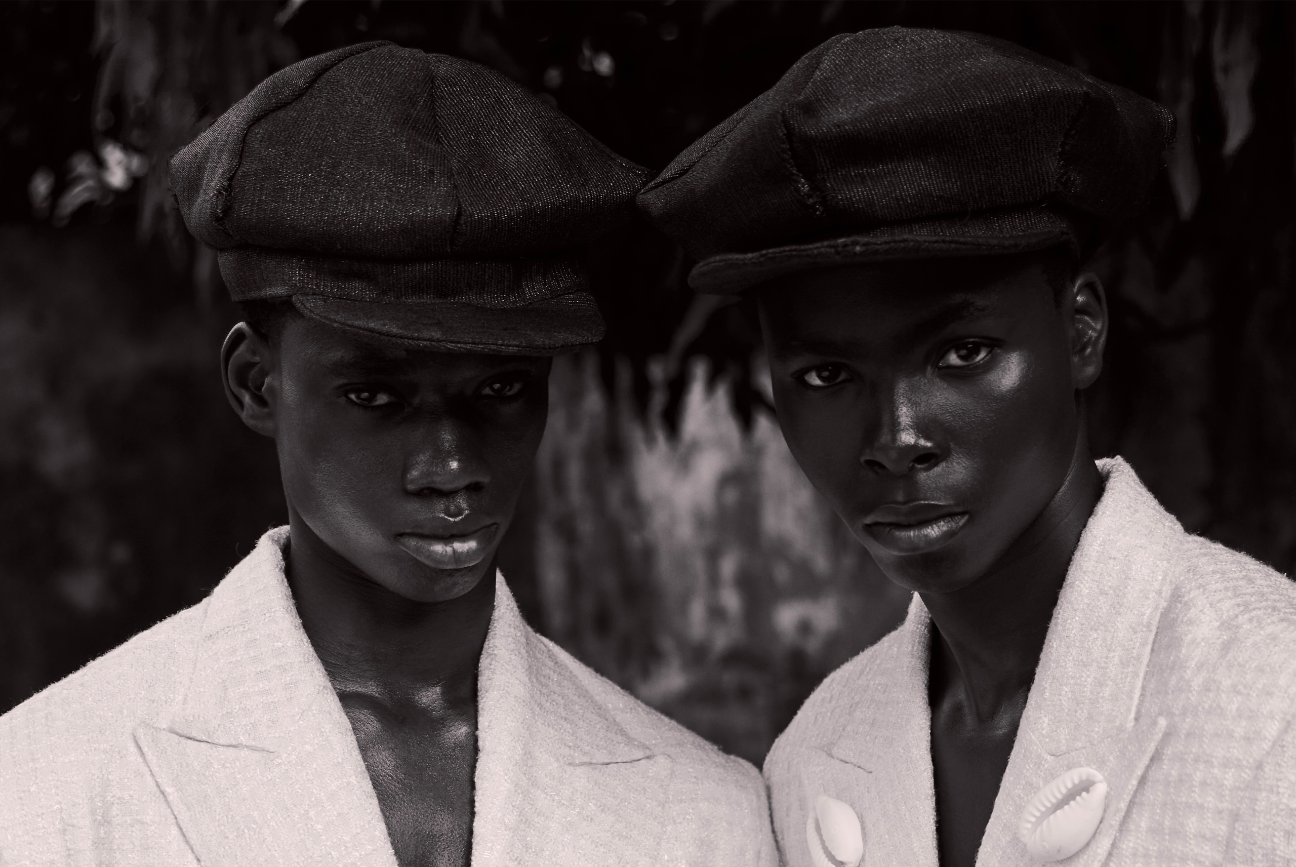 Two people in white coats and hats, gazing seriously in a monochrome setting.