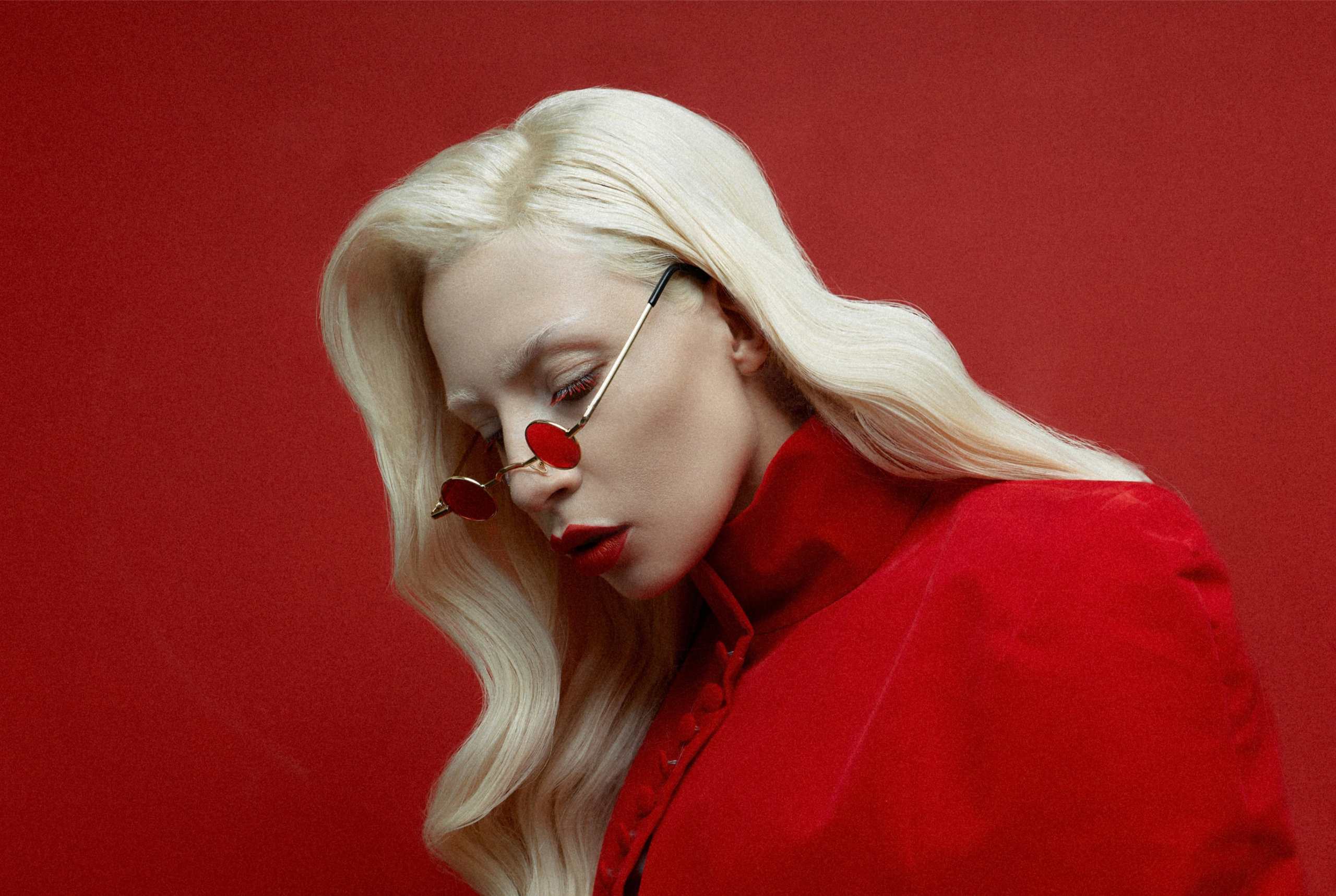 Elegant blonde with red sunglasses in chic red outfit.