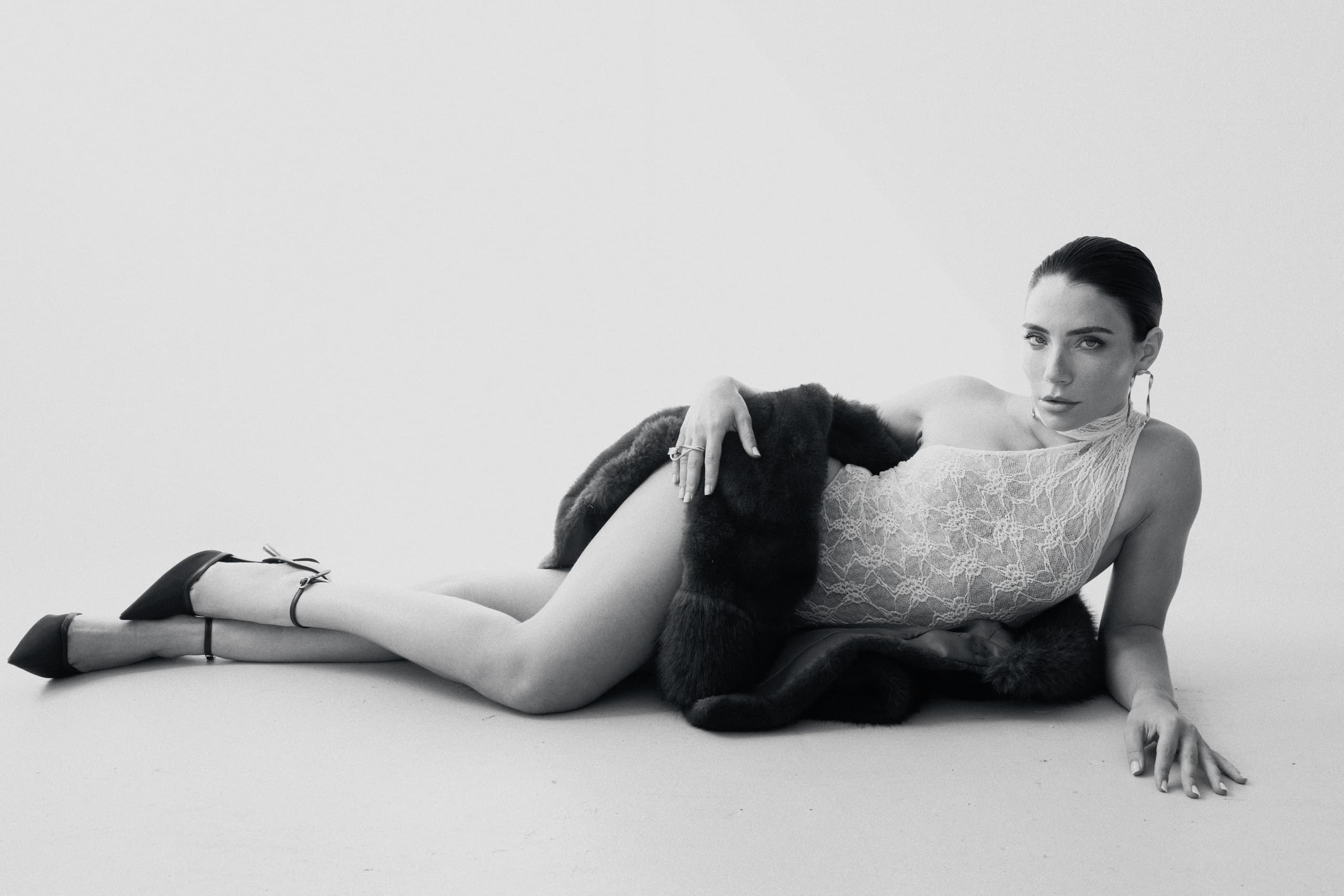 Stylish woman in lace outfit and fur coat posed gracefully on the floor.