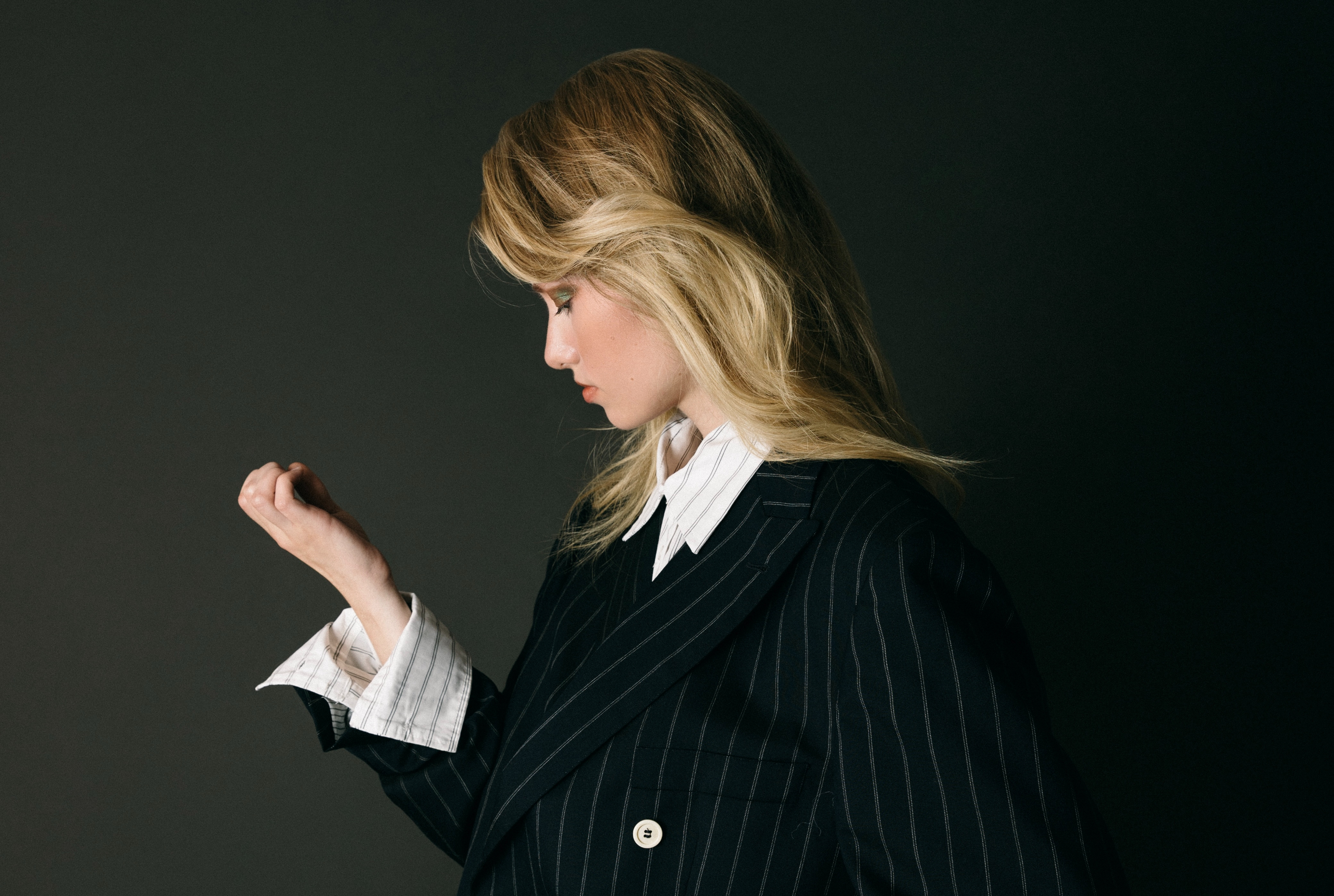 Profile of a woman in a pinstripe suit, showcasing elegant fashion style.