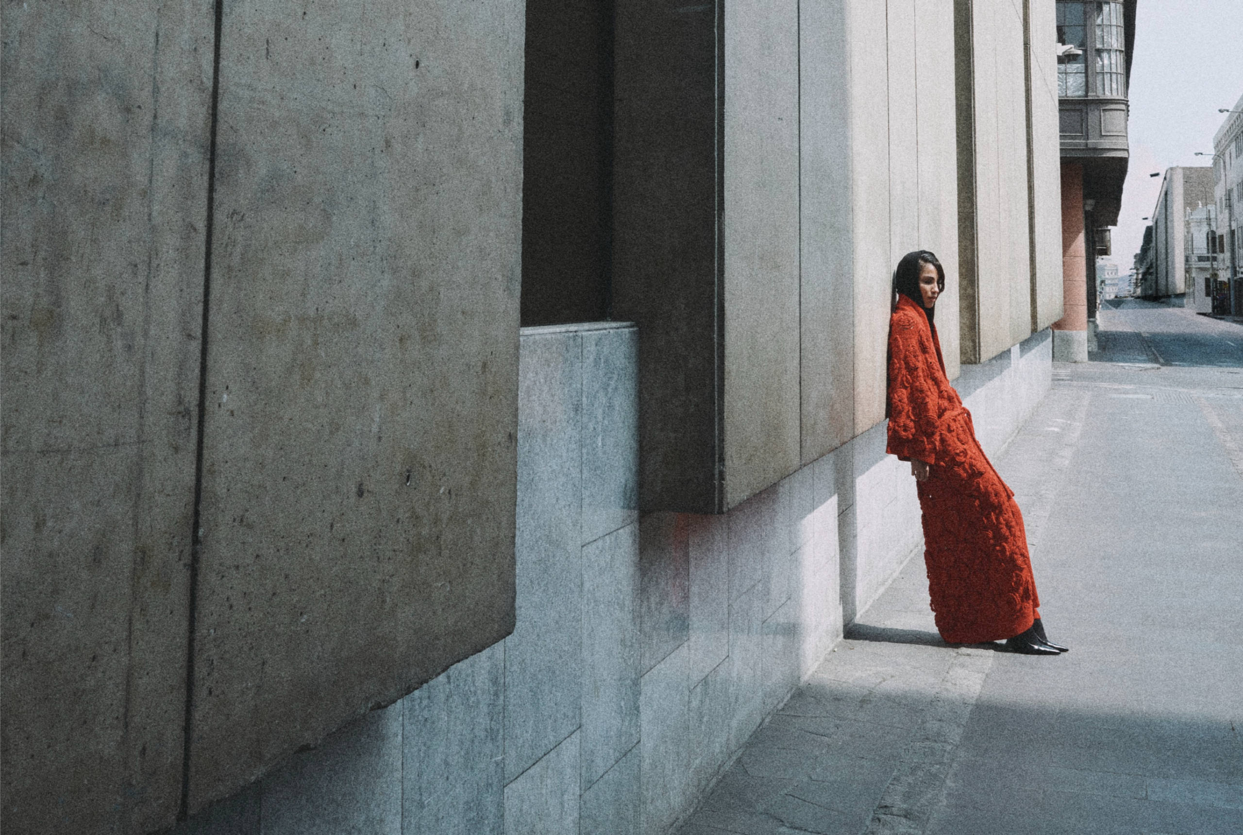 Person in red dress against urban wall, creating a striking contrast.
