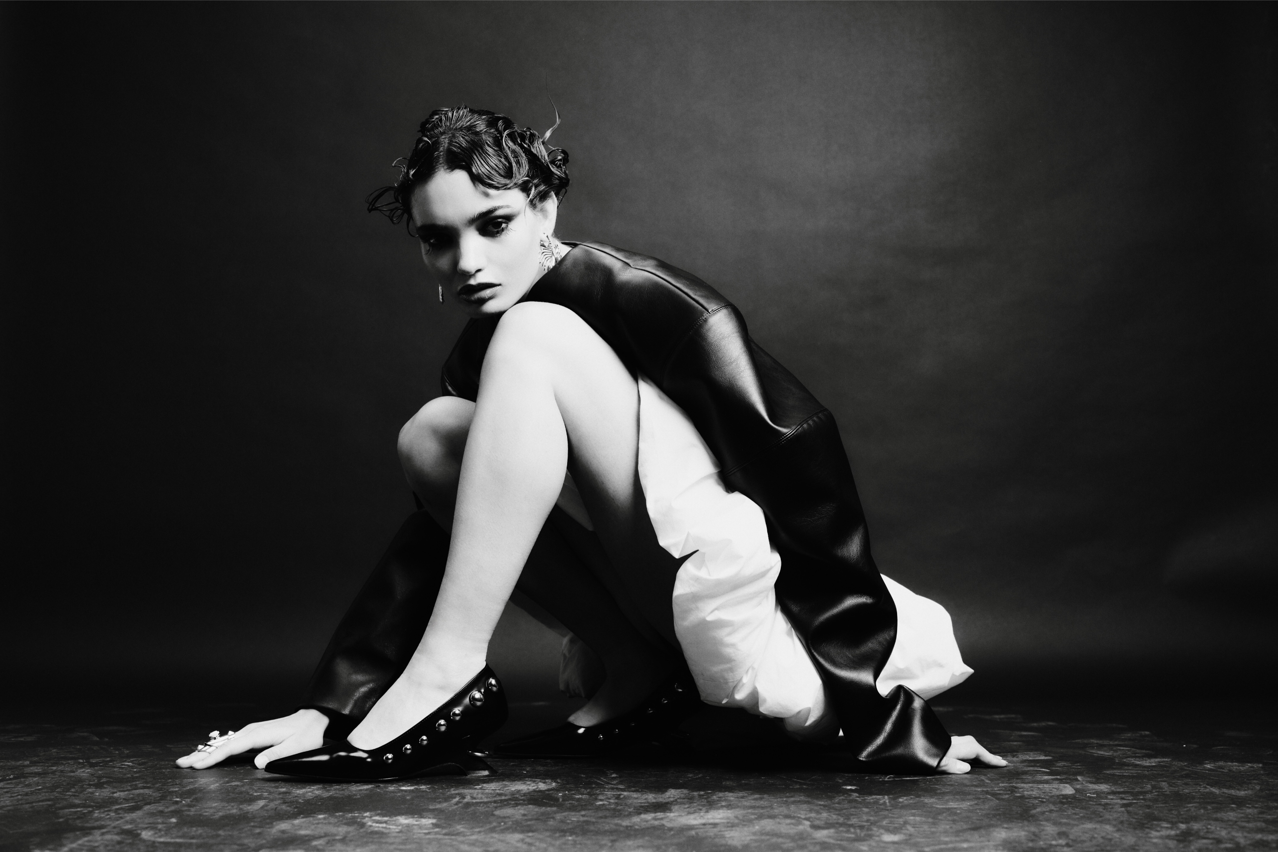 Fashionable woman in edgy black-and-white studio portrait, striking a pose.