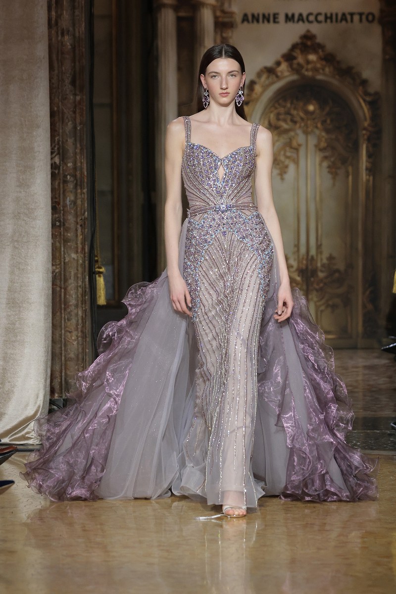 Elegant model in a shimmering lavender gown walking the runway.
