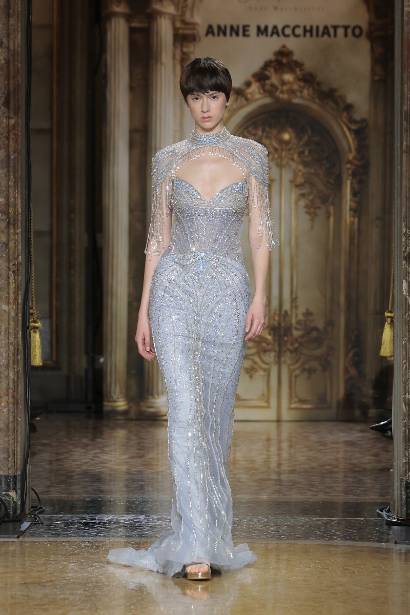 Model in elegant evening gown on fashion runway.