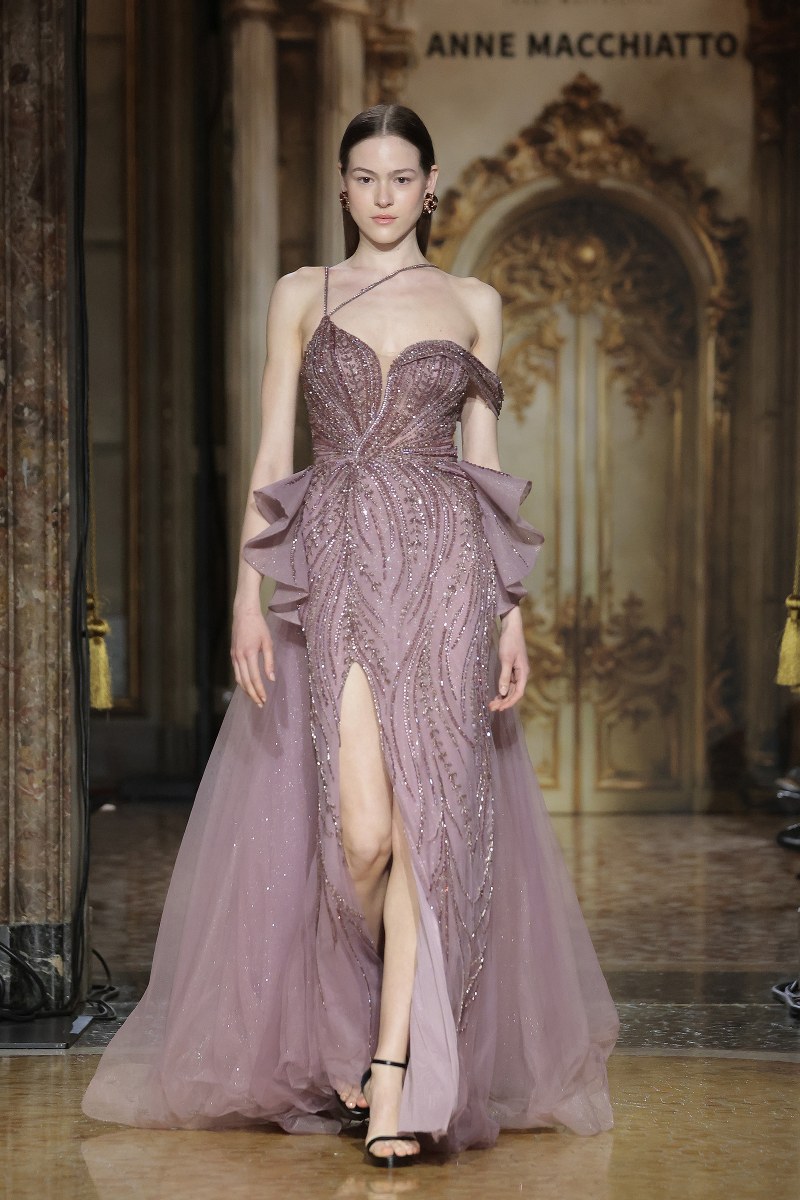 Elegant model in shimmering lavender gown on runway.
