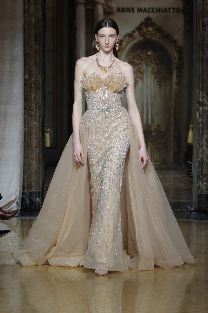 Elegant gown on runway at fashion show, showcasing detailed design and craftsmanship.