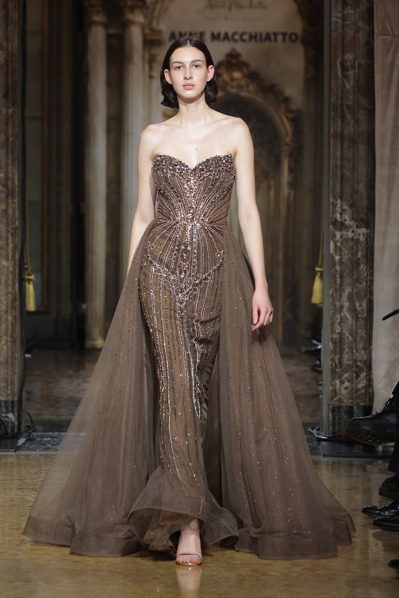Model in an elegant beaded gown walking a fashion show runway.