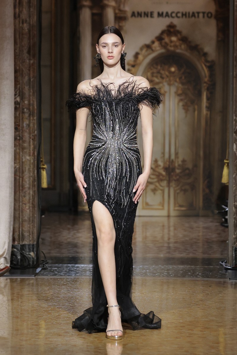 Model wearing a stunning black evening gown on the runway.