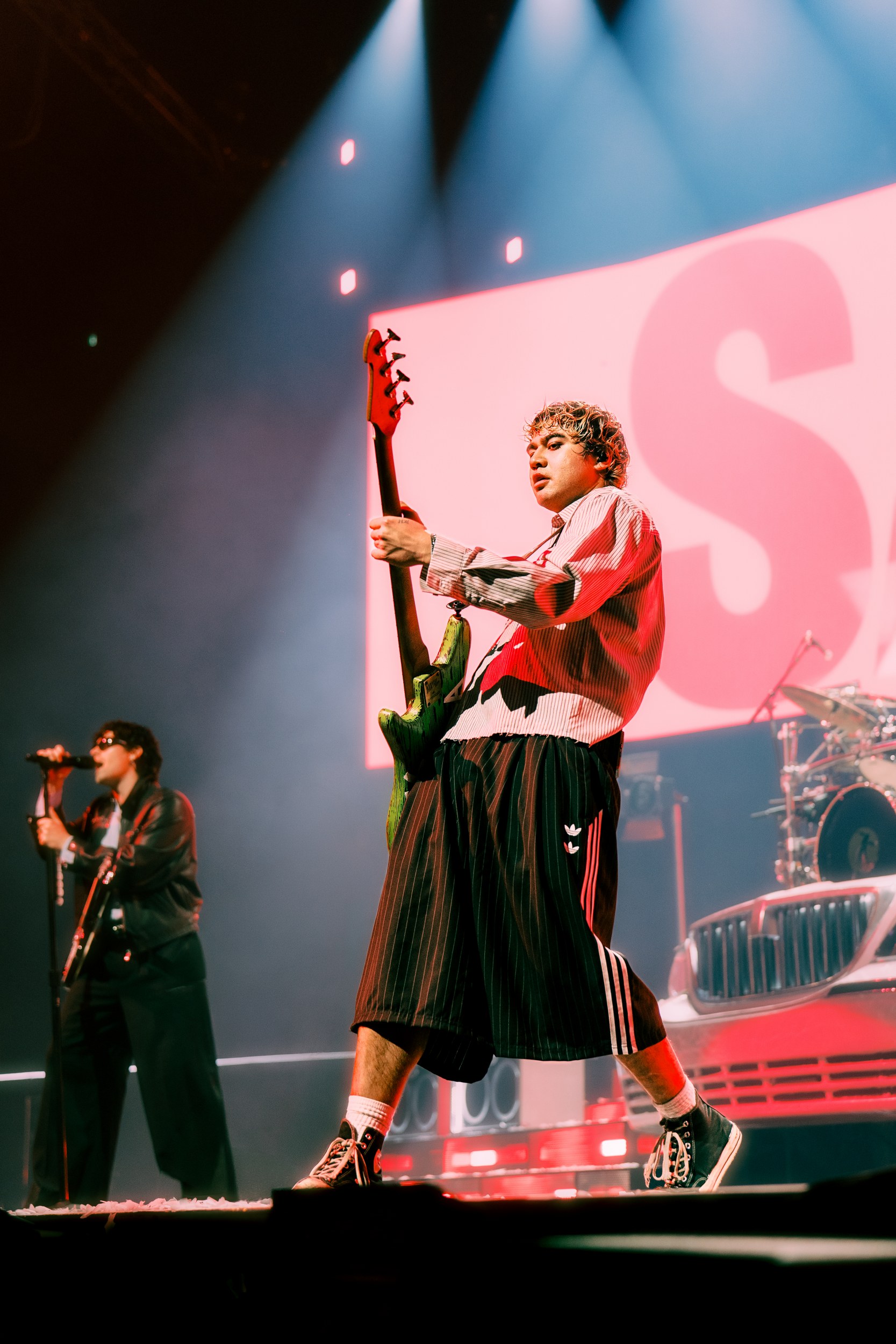 Bassist rocking the stage under vibrant lights during a live concert performance.