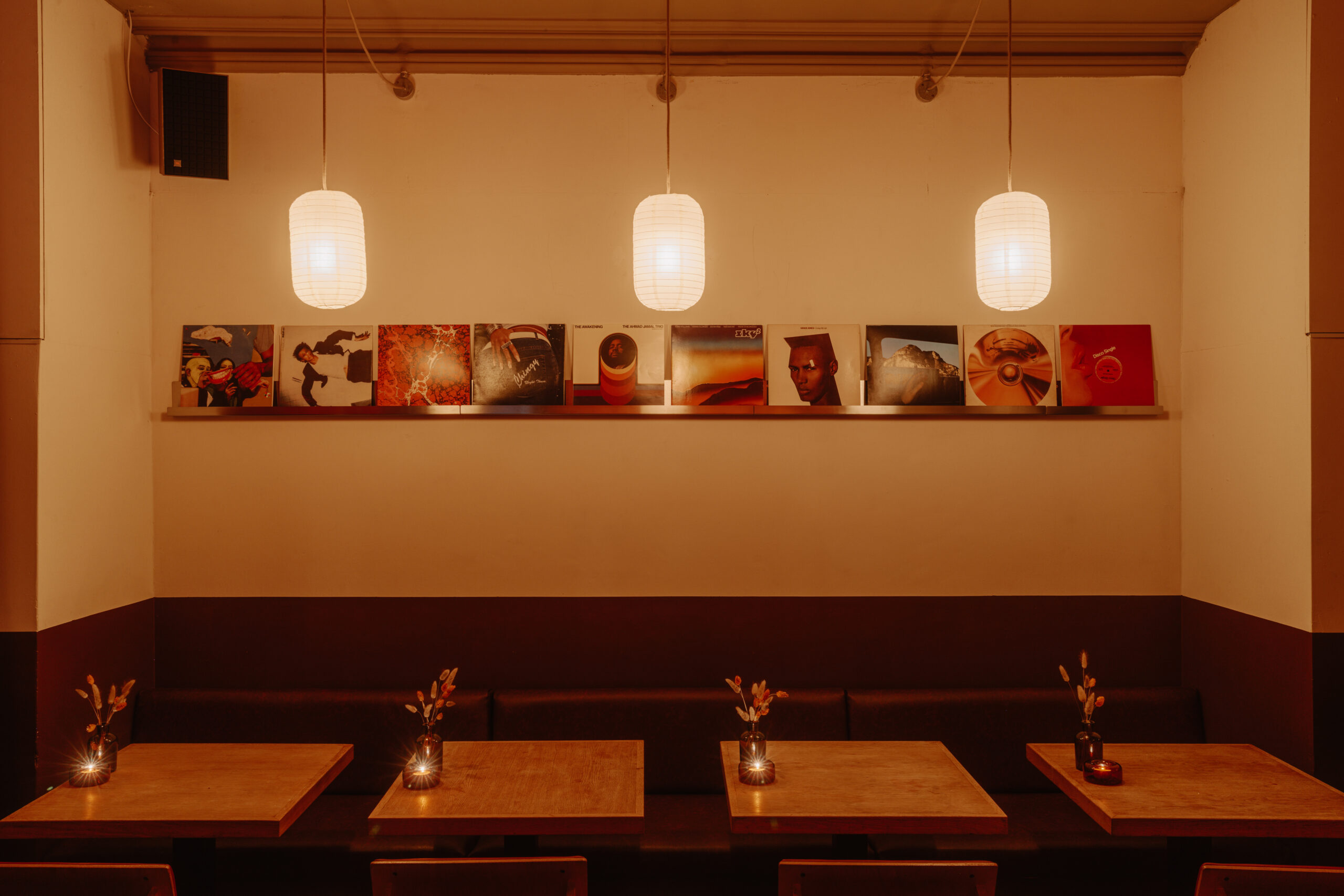Cozy cafe with vinyl records on the wall and warm pendant lighting.
