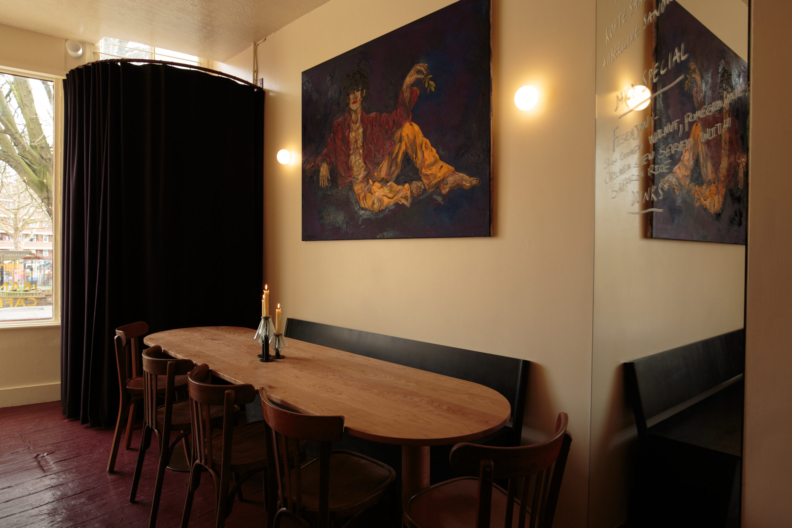 Cozy dining room with art and wooden table for eight, dim lighting and candles.