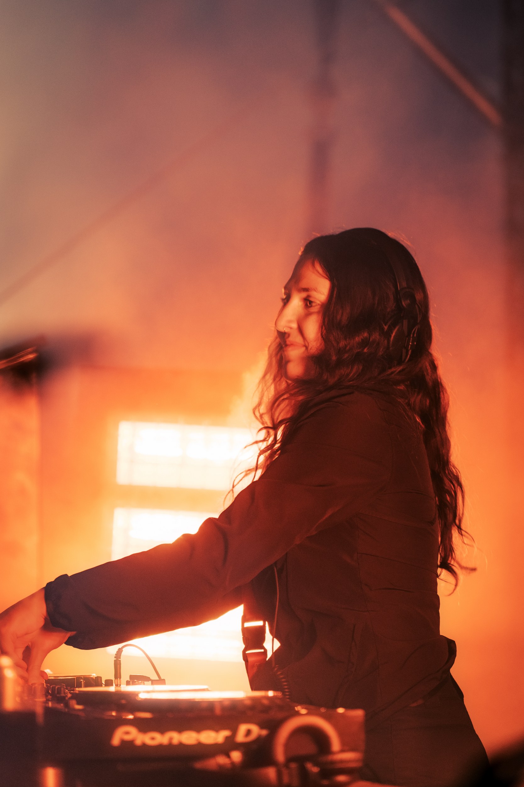 DJ performing on stage with bright lights in the background.