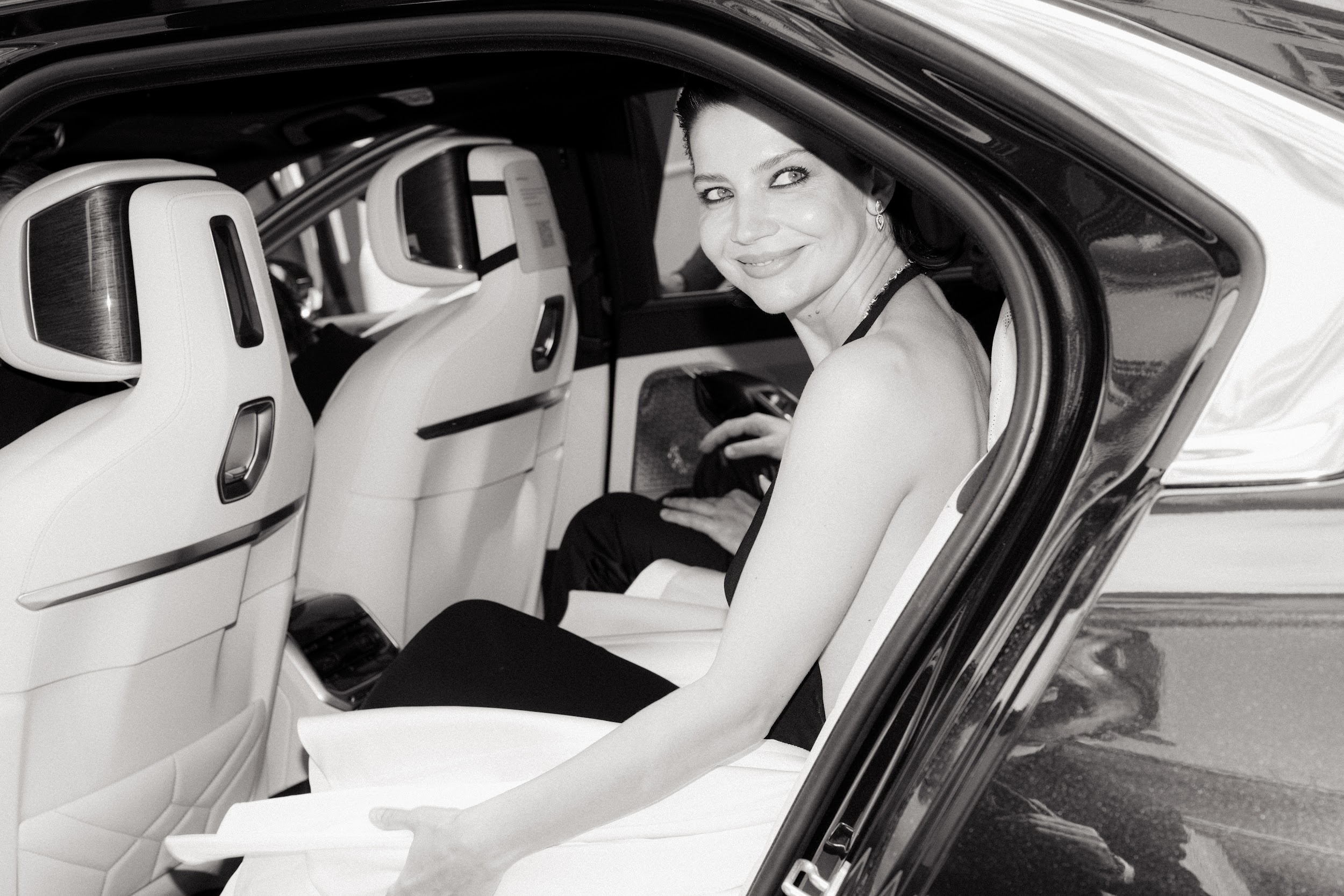 Woman smiling in a luxury car, black and white photo.