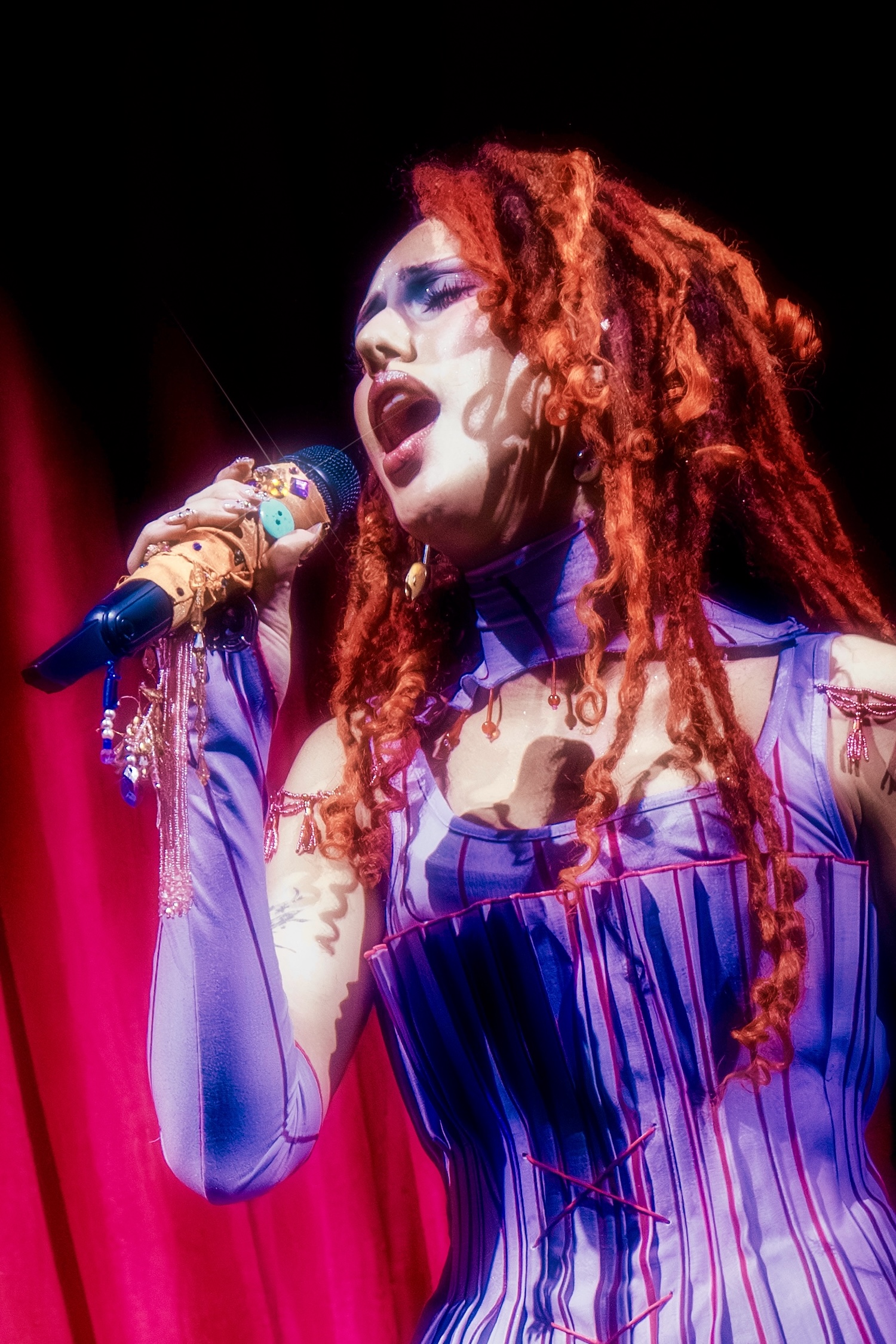 Singer performing passionately on stage with vibrant costume and dramatic lighting.