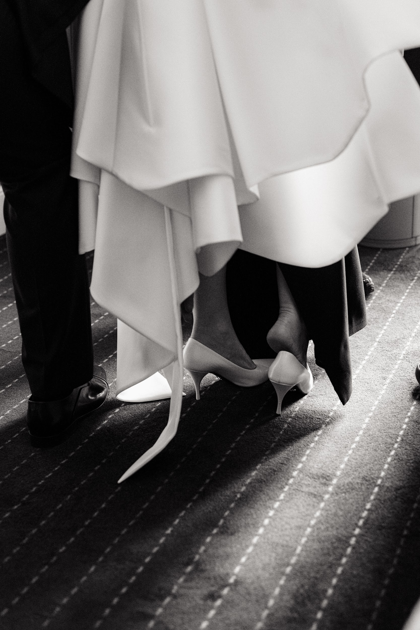 Bride and groom footwork, elegant white heels and dress hem.