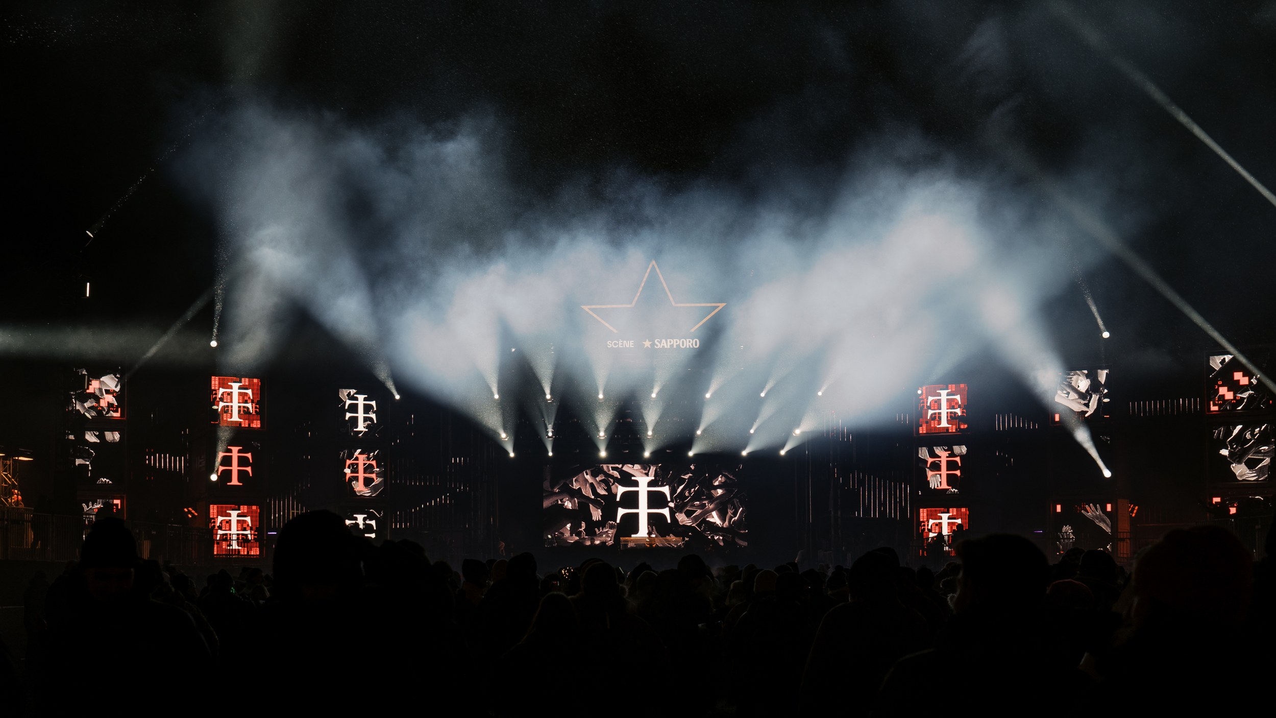 Concert stage with vibrant lights and crowd at night, creating an electrifying atmosphere.