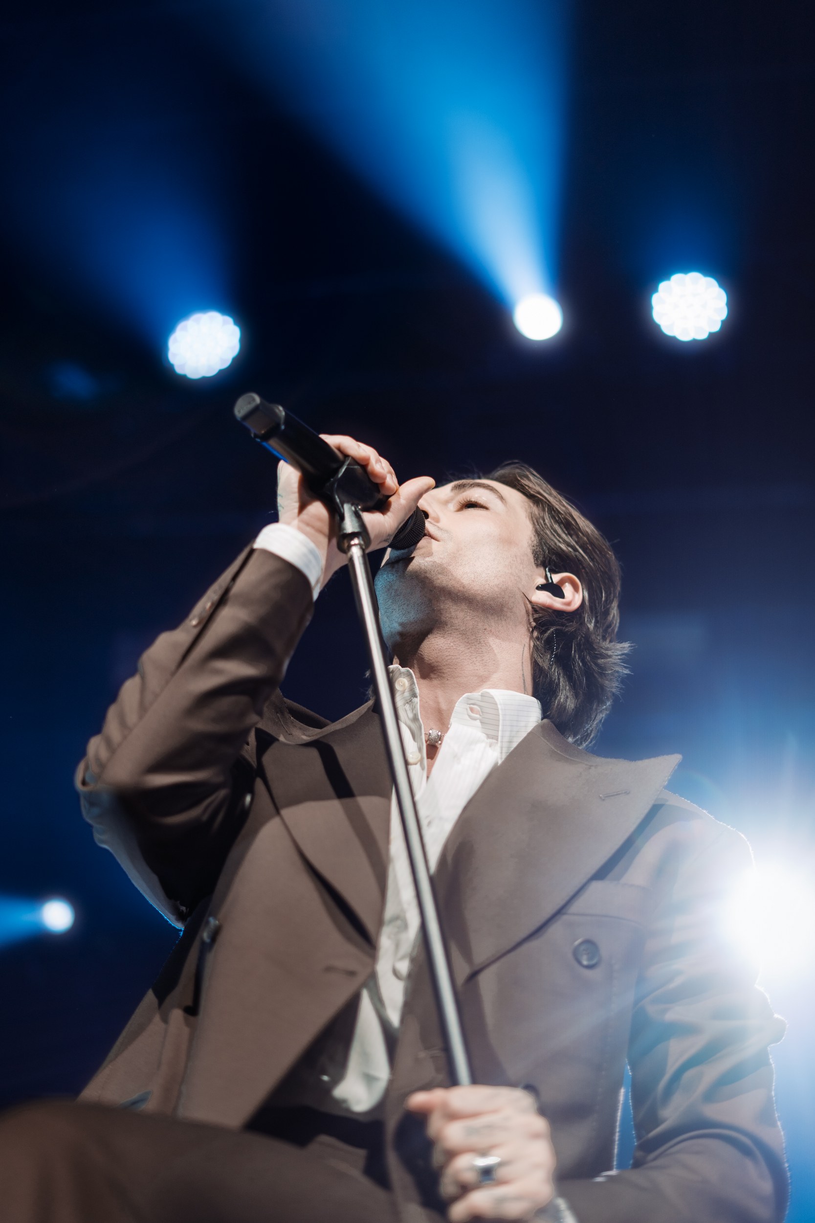Singer performing passionately on stage under vibrant blue spotlights.