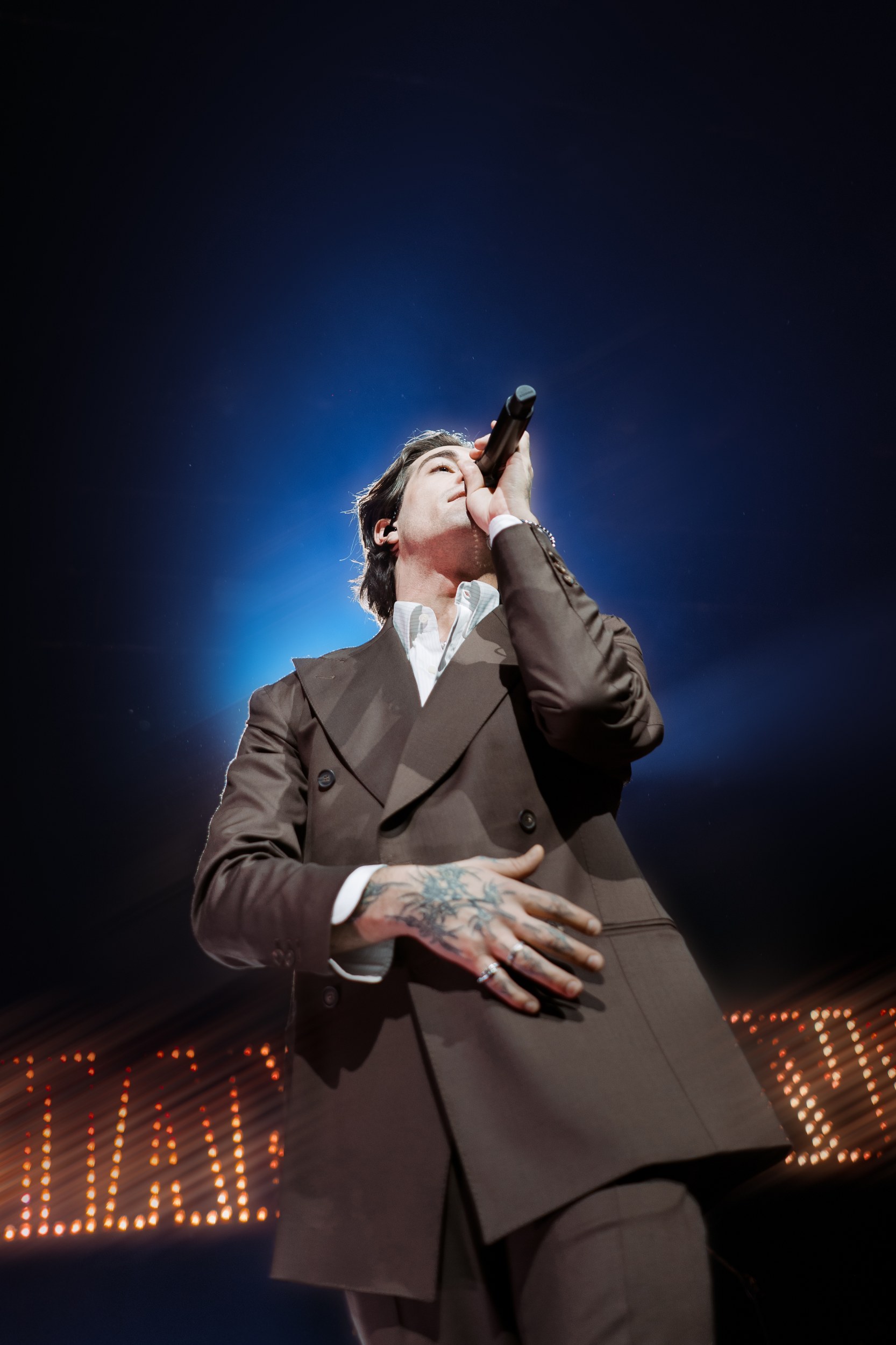Singer performing on stage with dramatic lighting and intense expression.