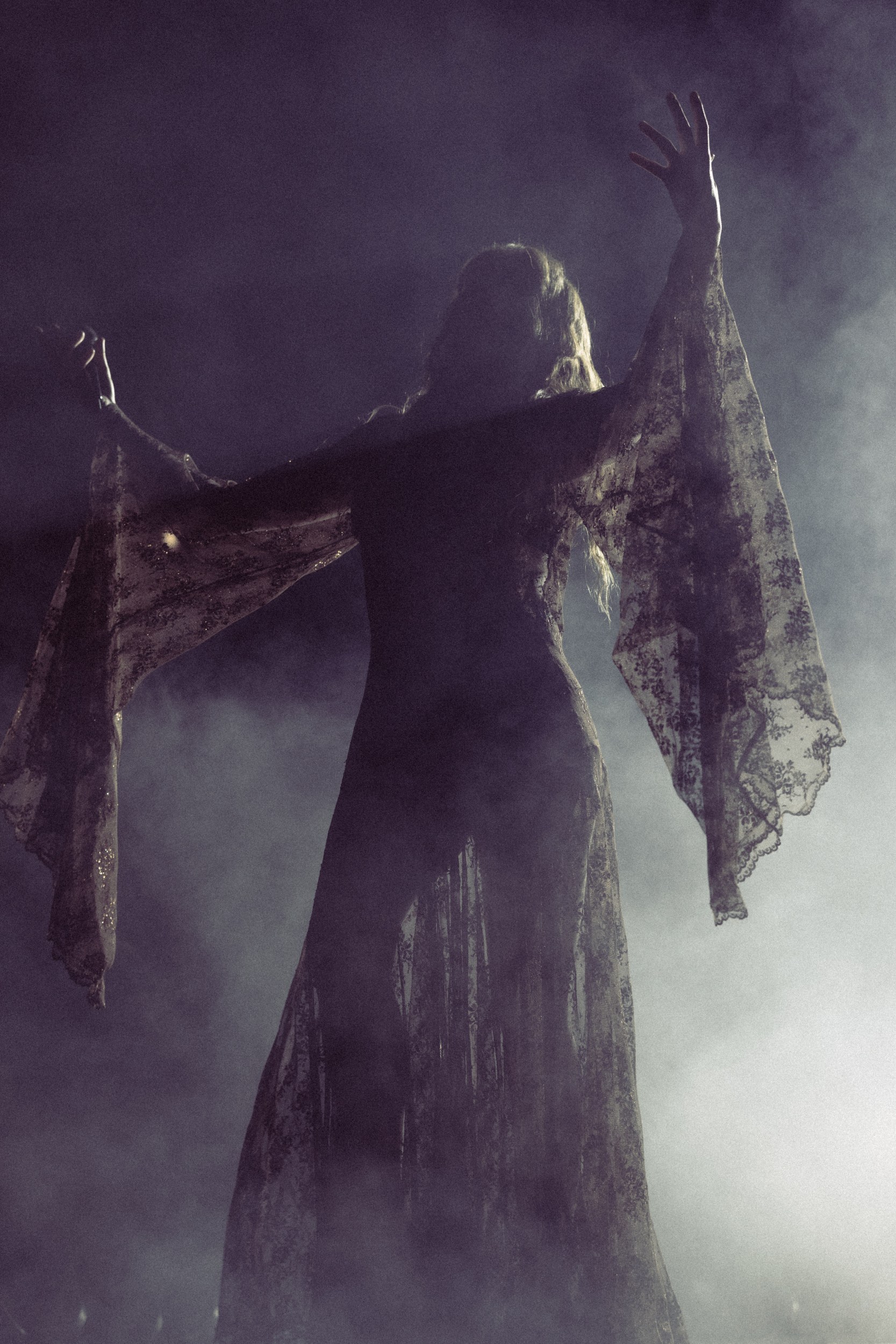 Silhouetted figure with flowing sleeves in ethereal misty atmosphere.