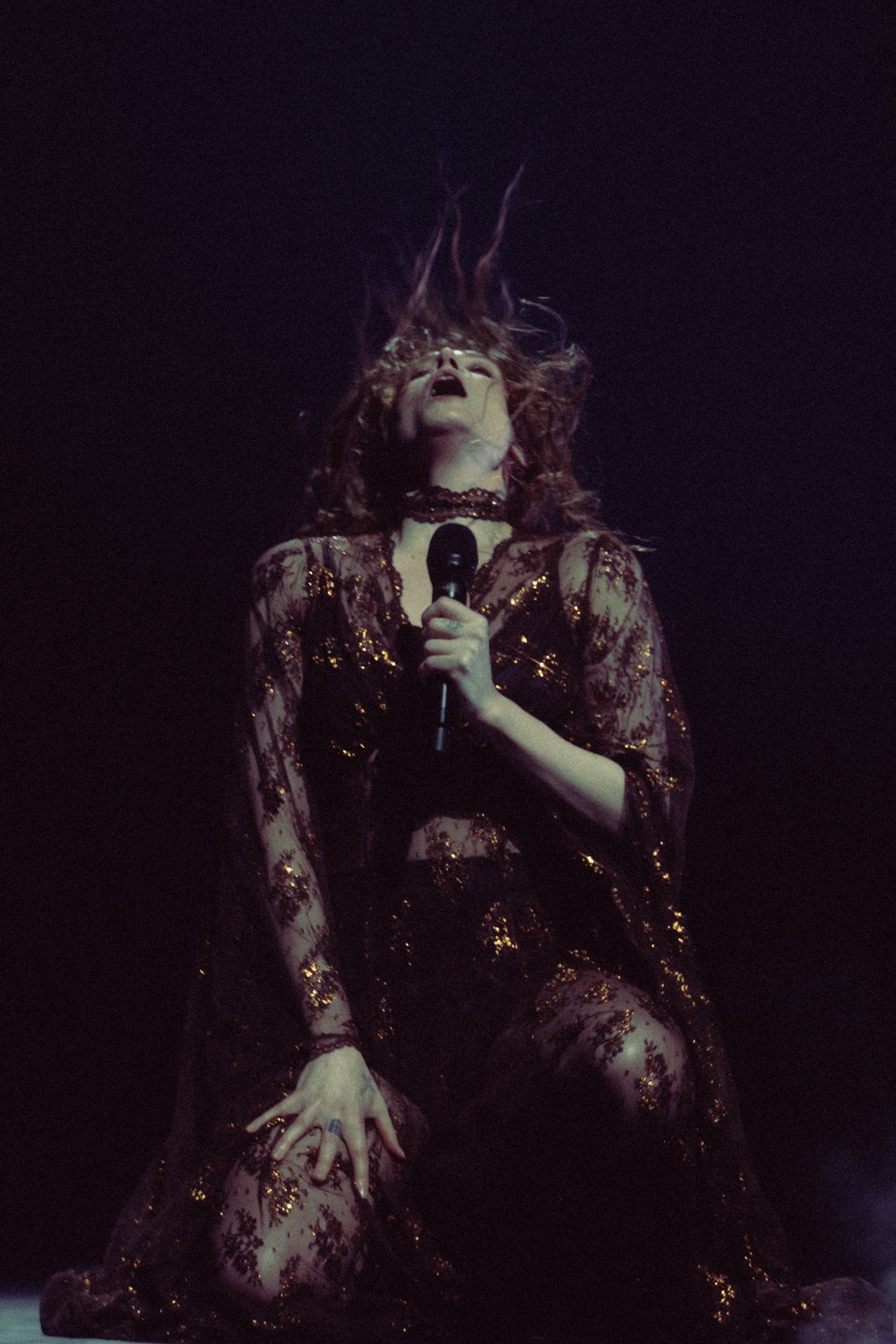 Performer passionately singing on stage with dynamic lighting and expressive gestures.