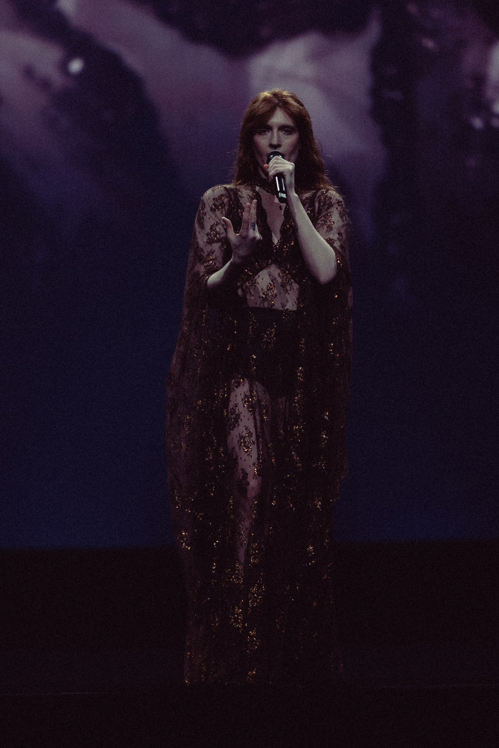 Singer performing passionately on stage with dramatic lighting.