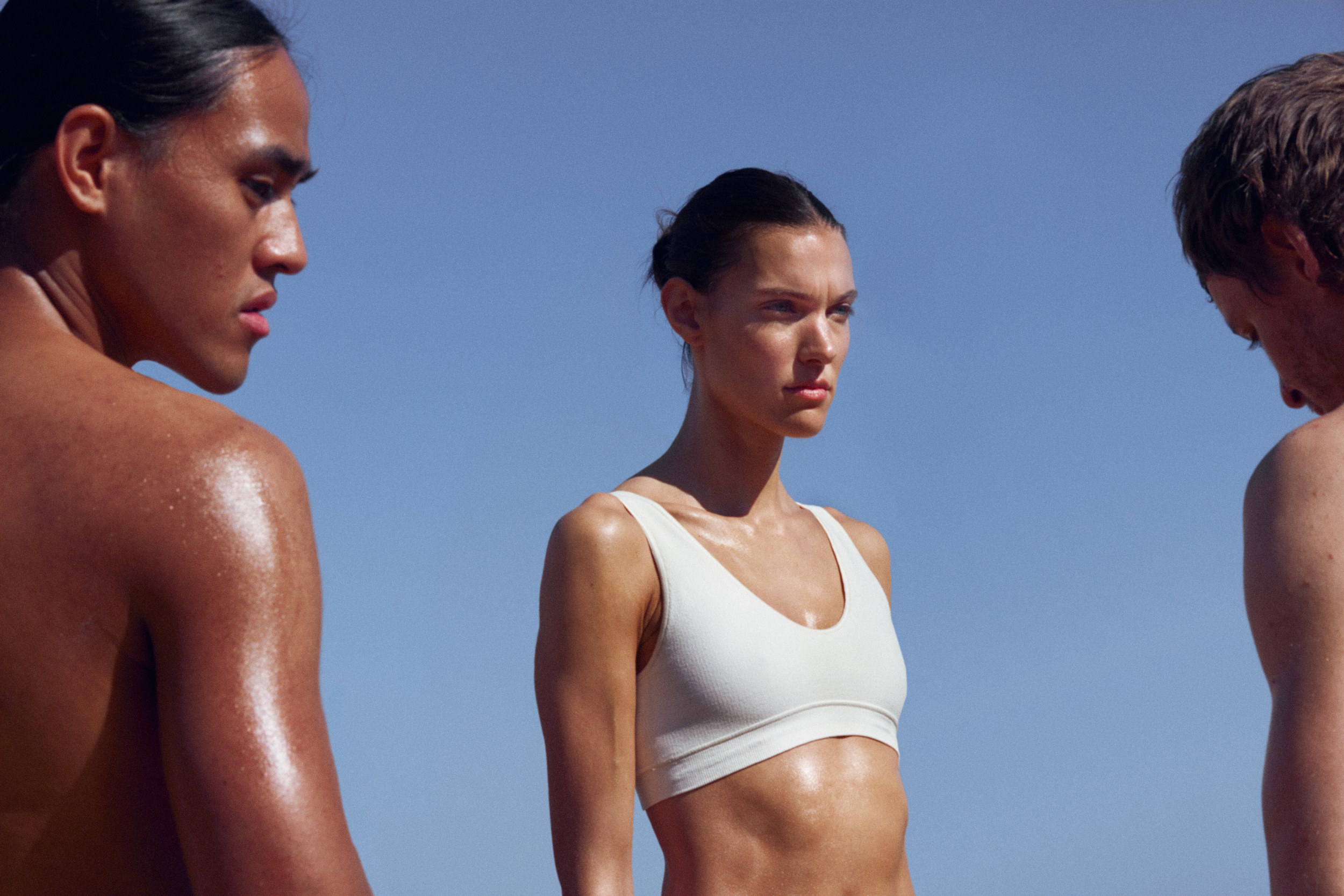 Three athletic individuals under the sun with blue sky backdrop.