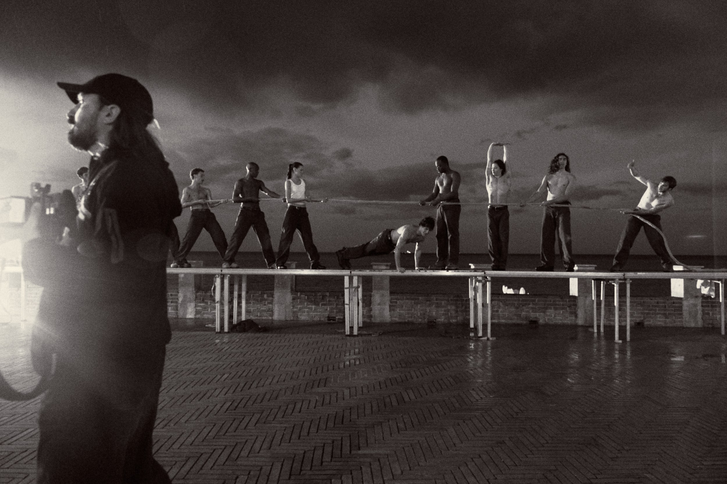 Group performing synchronized dance routine on an outdoor platform at night.