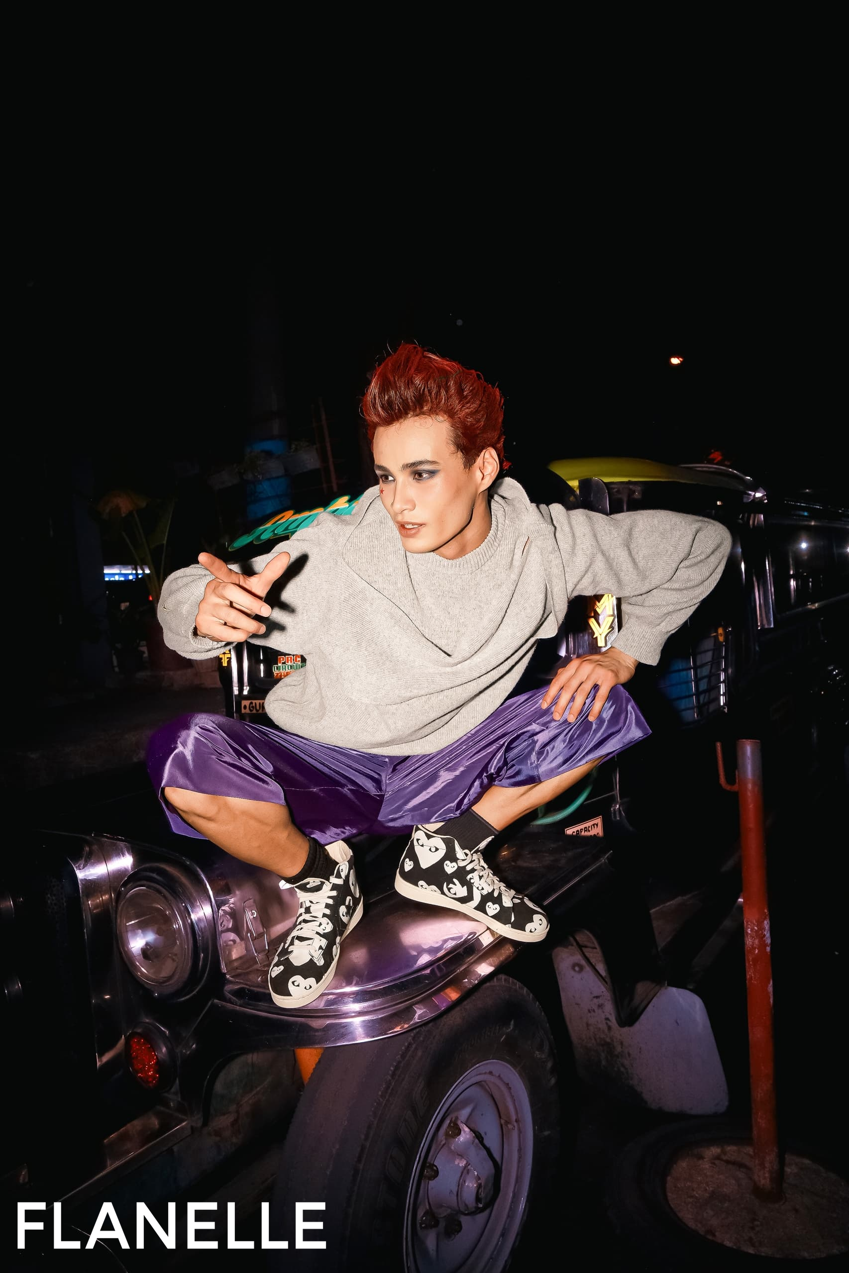 Model posing on a jeep, wearing stylish streetwear with bold red hair.