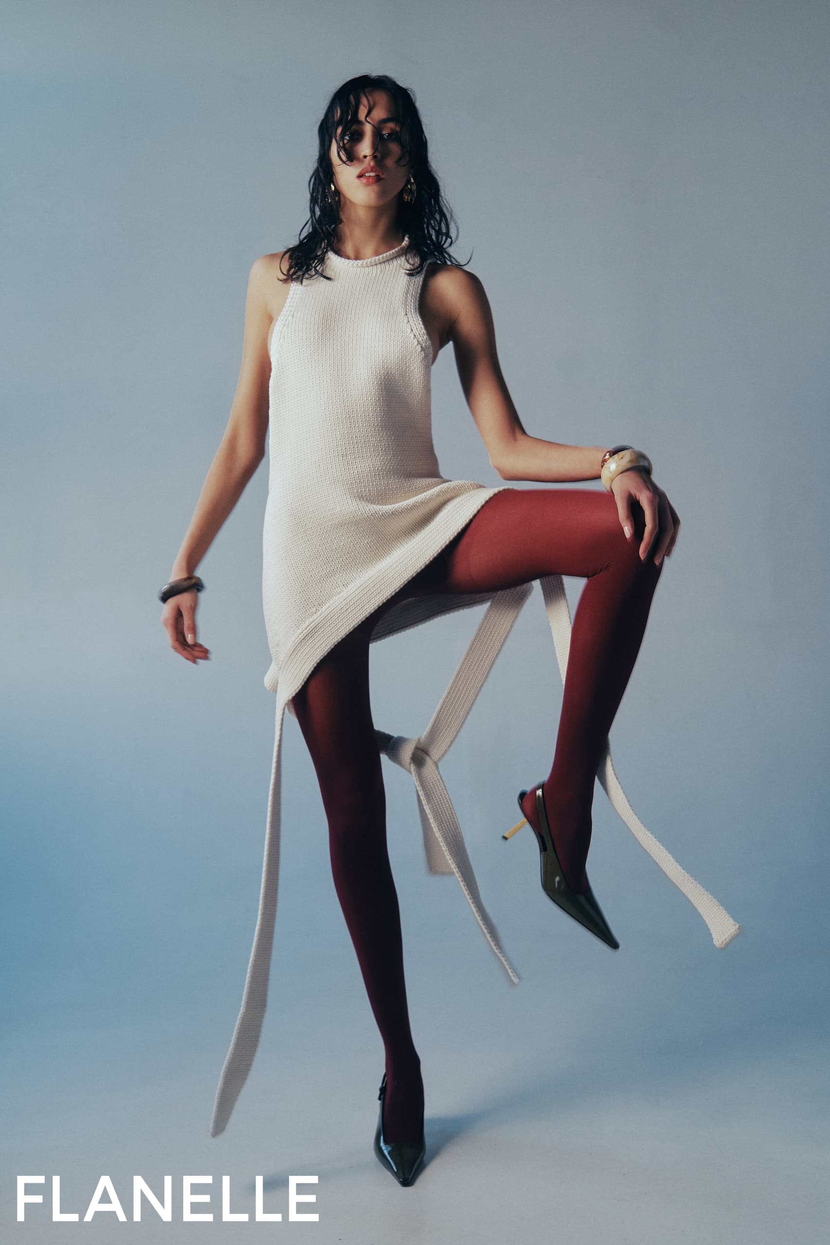 Stylish woman in white dress and red tights posing elegantly. Fashion photography.