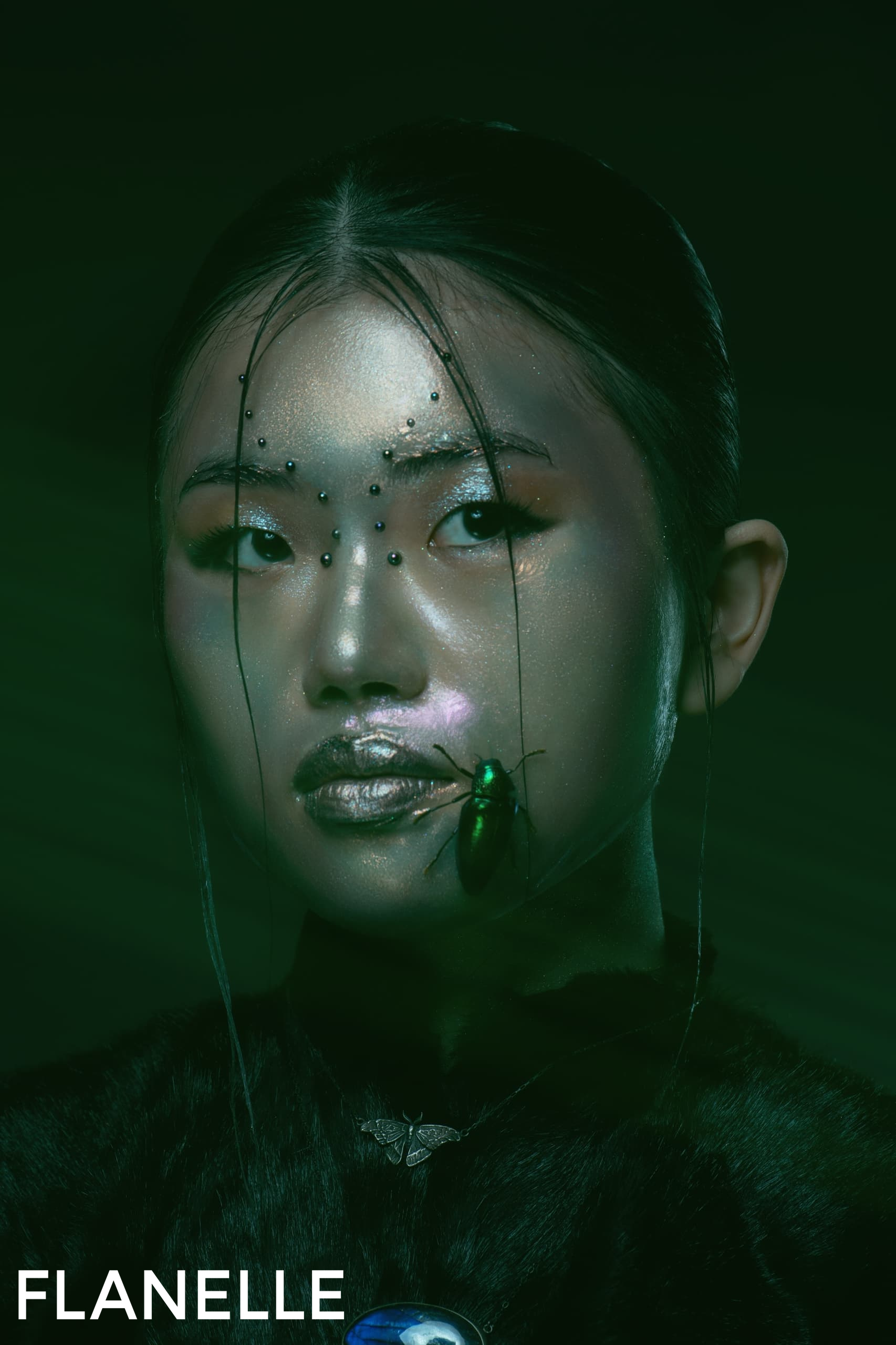 Futuristic makeup art with beads and shiny green insect on face, dark aesthetic.