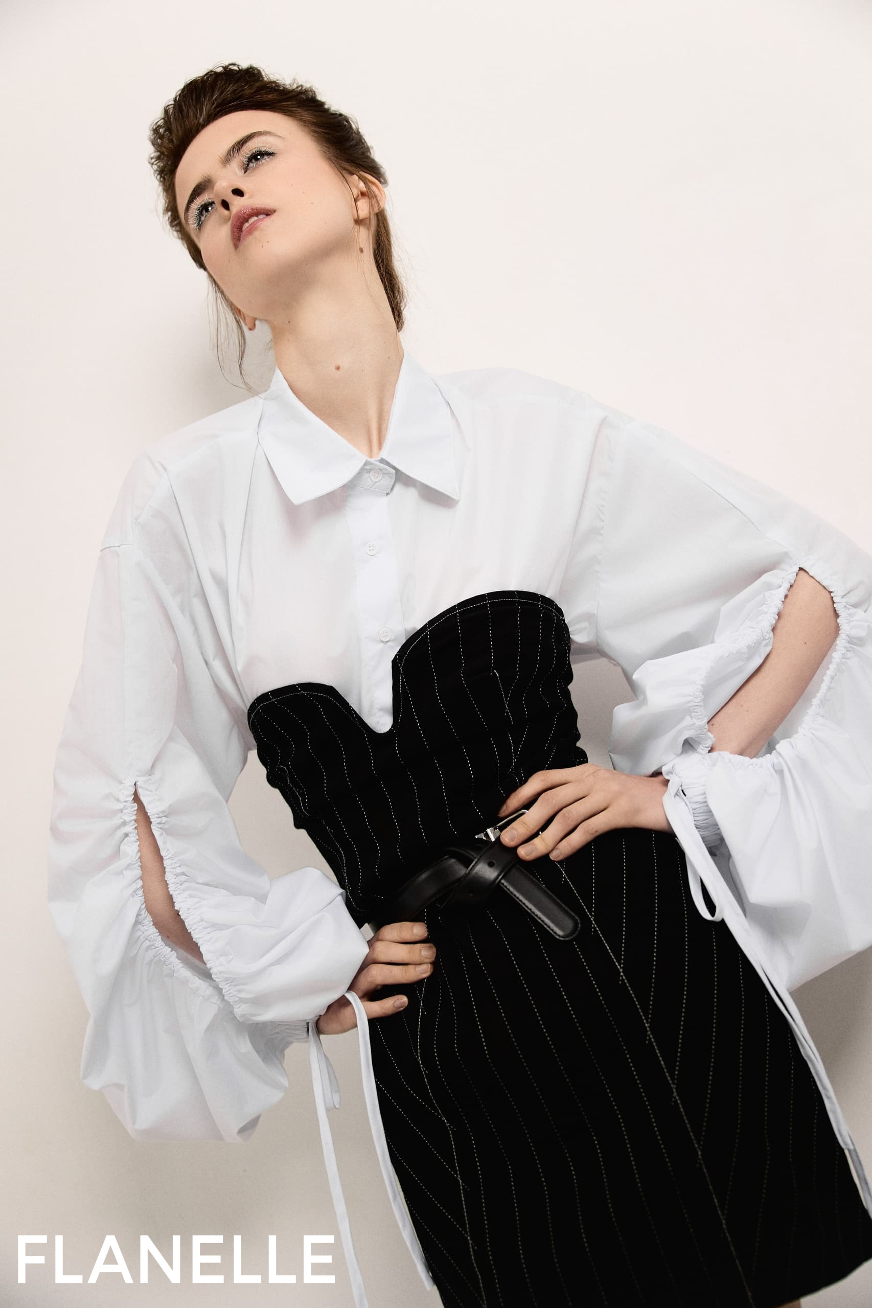 Fashion model poses in chic white shirt and black corset dress from Flanelle.