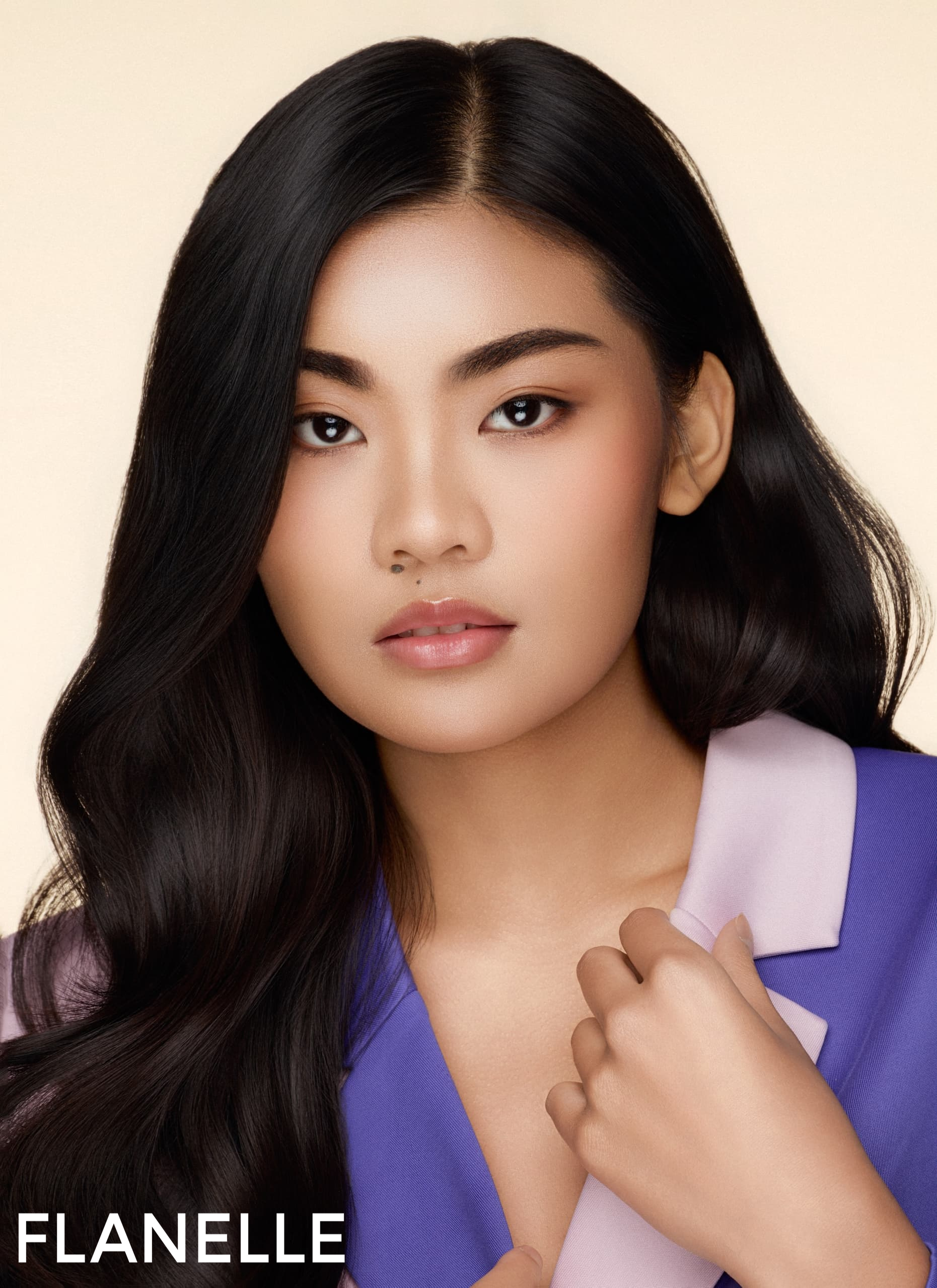 Portrait of a woman with long black hair and a purple collared outfit.