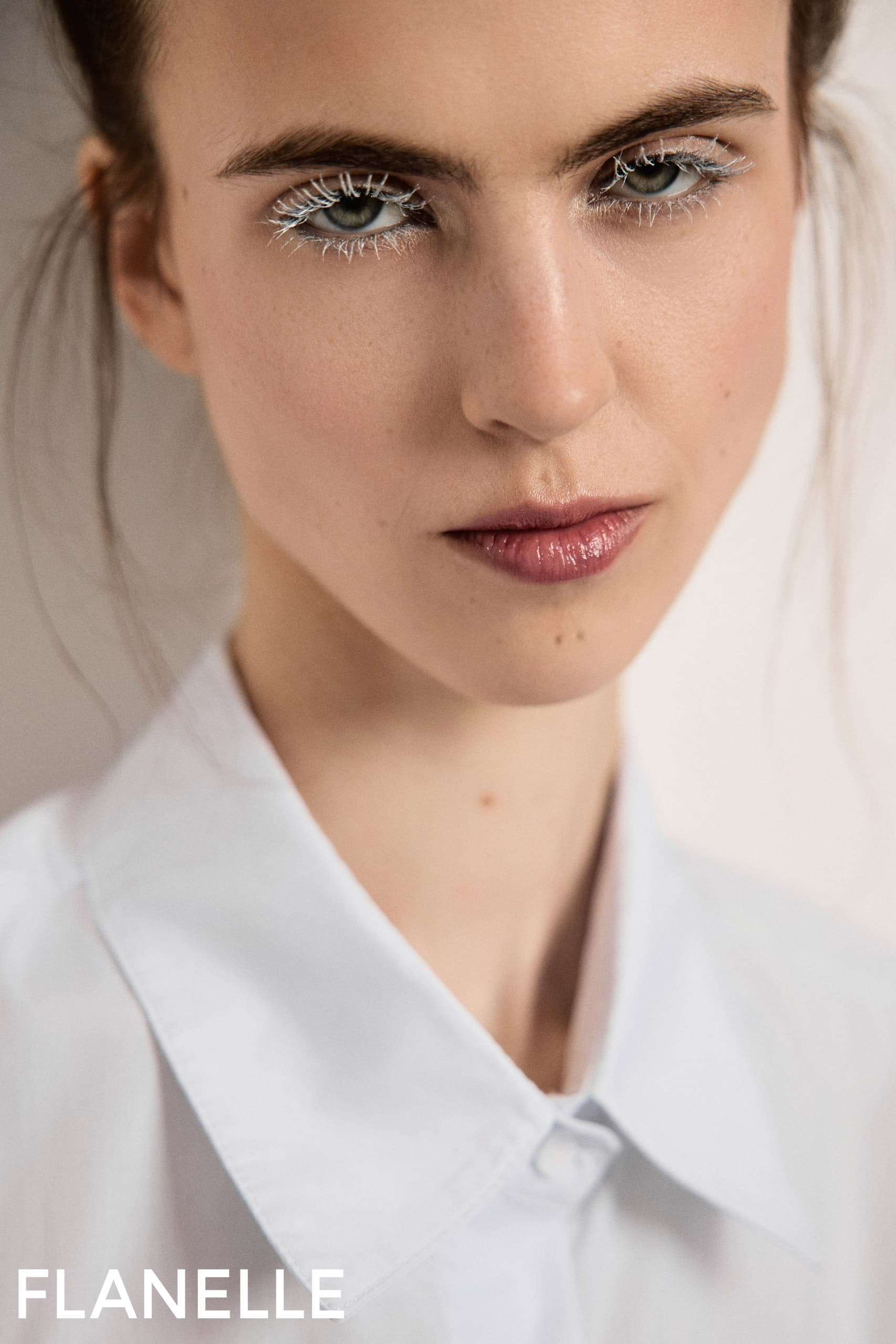 Close-up of model wearing white shirt with white eyeliner. Flanelle Magazine.