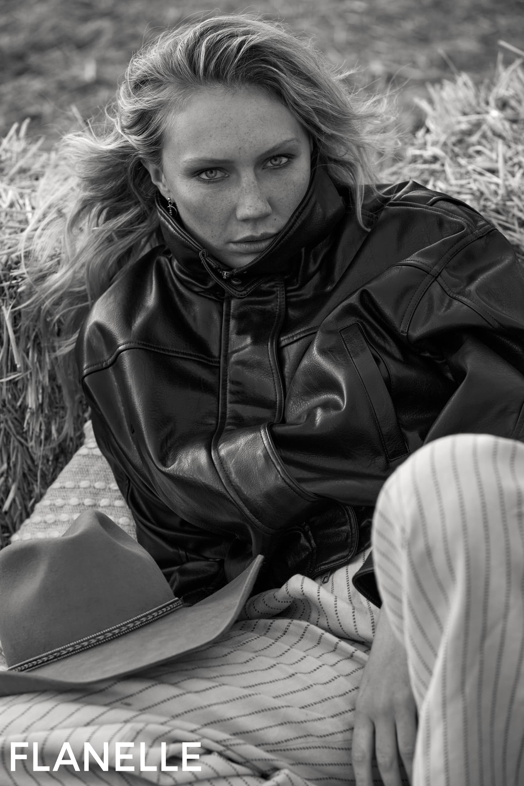 Black and white photo of a woman in a leather jacket with a cowboy hat nearby.