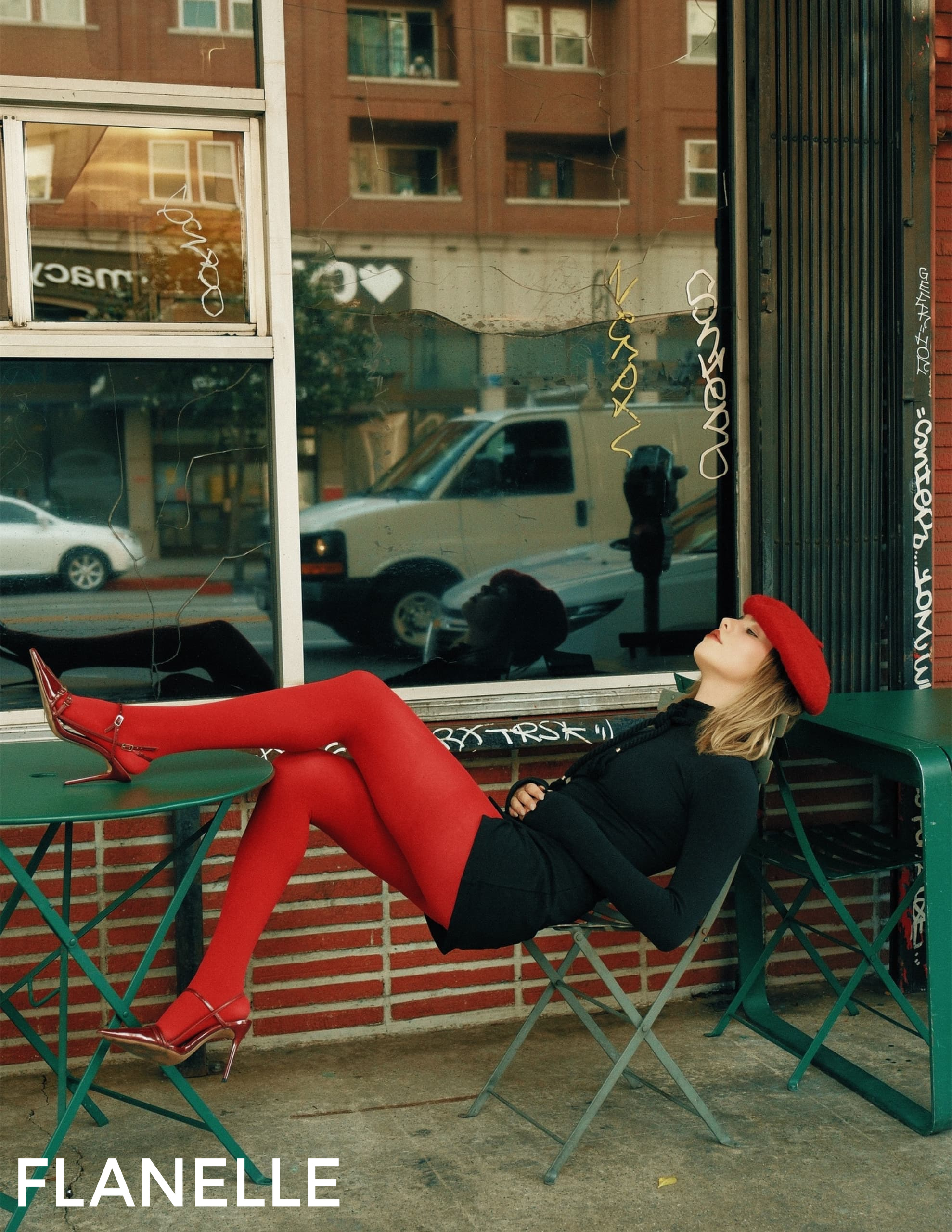 Stylish woman in red tights and beret lounges on a chair outside a shop.