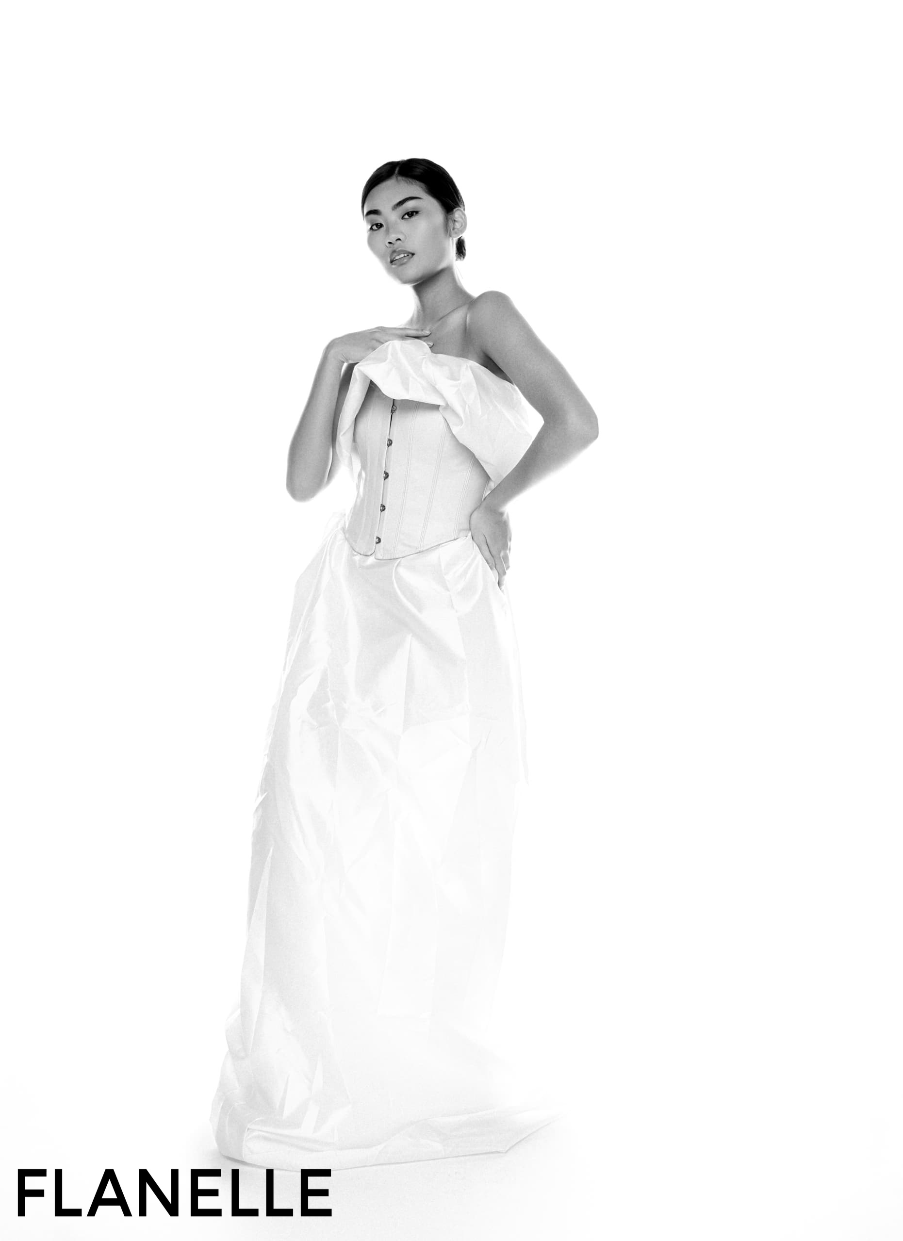 Fashion model in elegant white gown and corset, posing for Flanelle magazine.