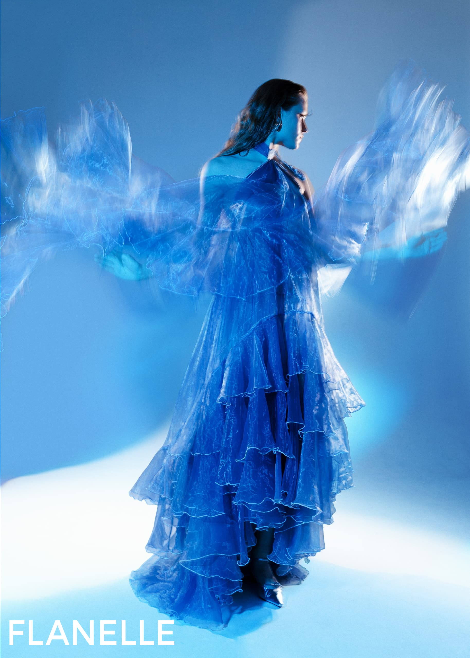 Elegant blue dress in motion, layered ruffles, artistic photography.
