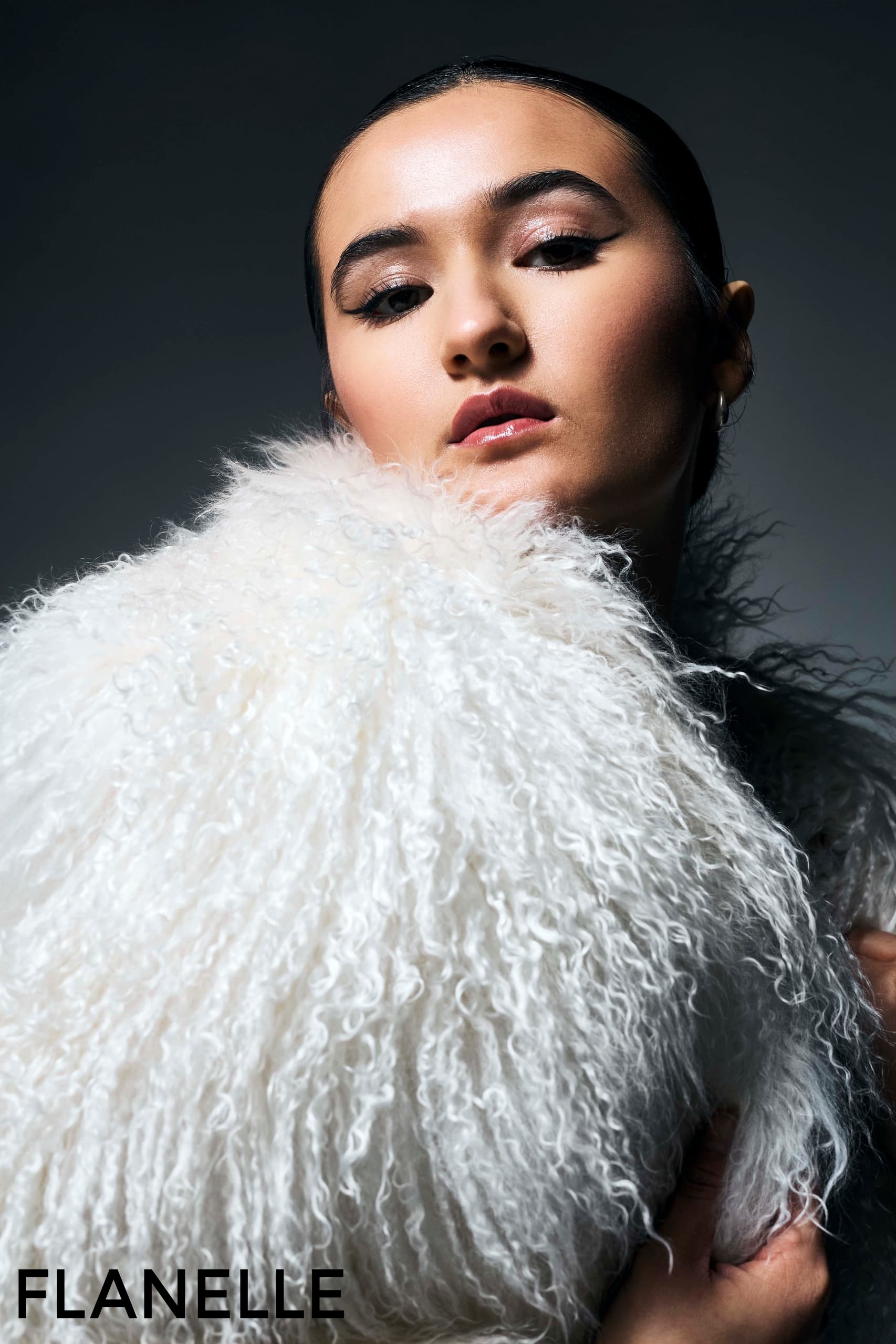 Fashion model in elegant white fur coat, striking pose for Flanelle magazine cover.