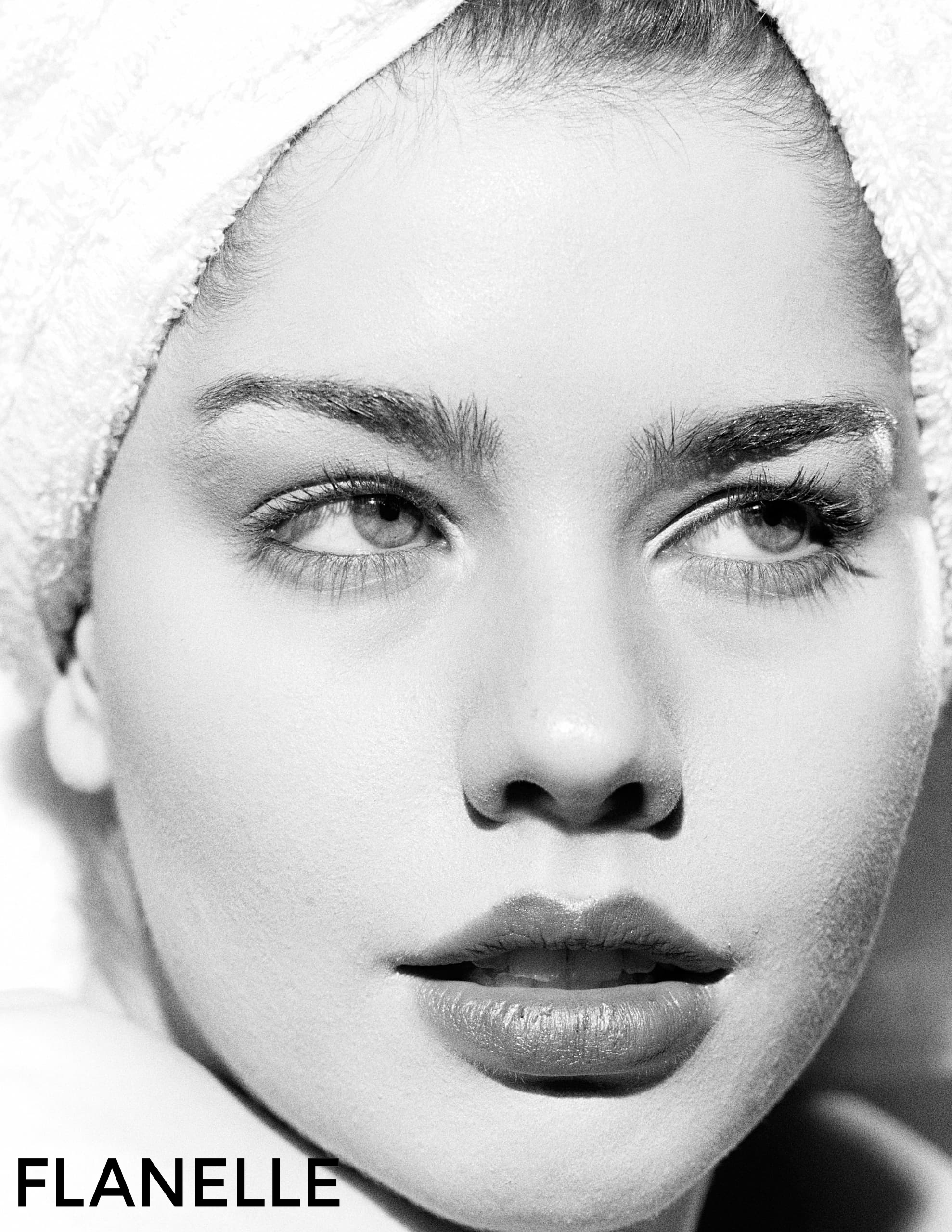 Monochrome close-up of a woman with a towel headwrap, showcasing beauty and elegance.