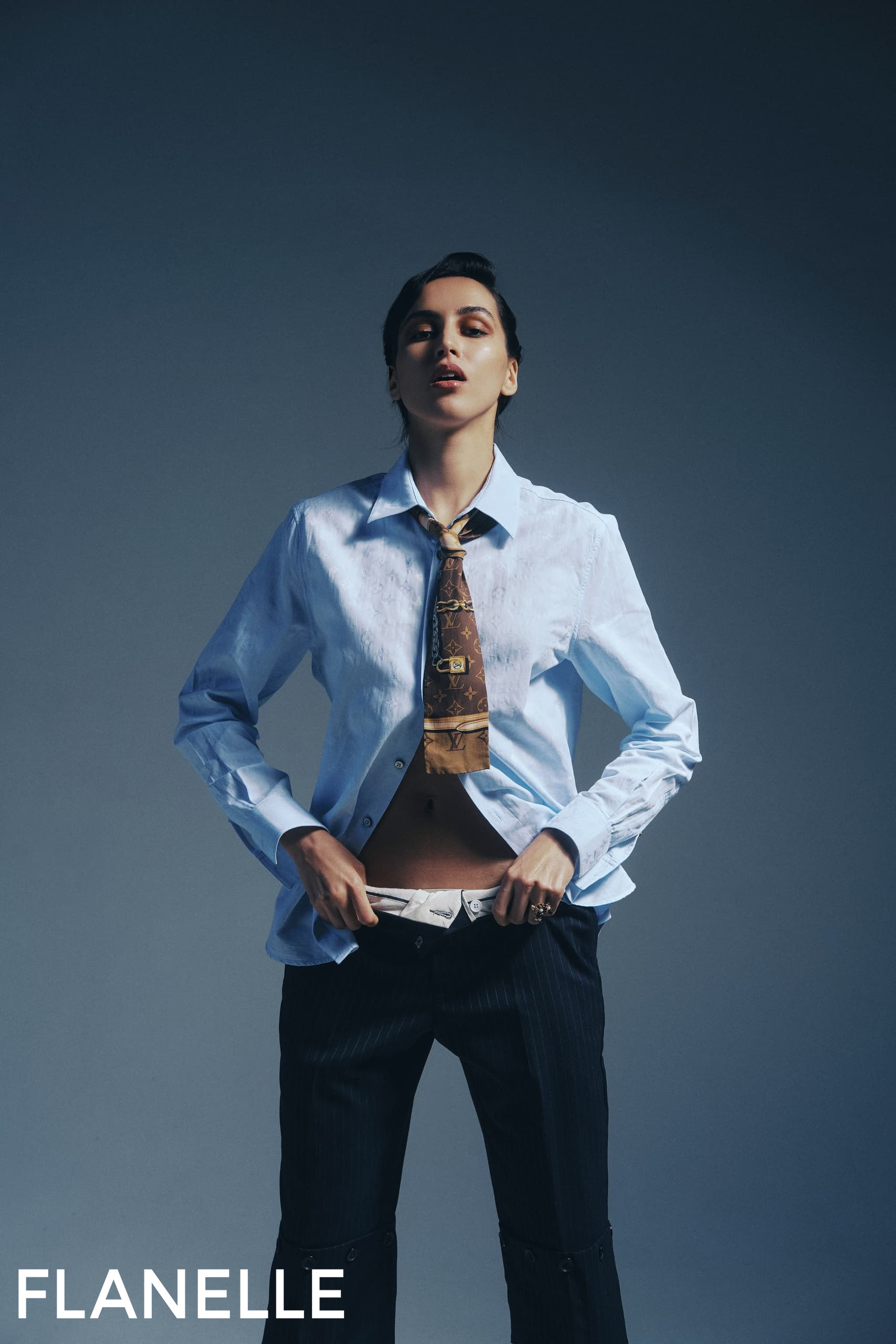Fashion model in shirt and tie, stylish pose against a dark background.