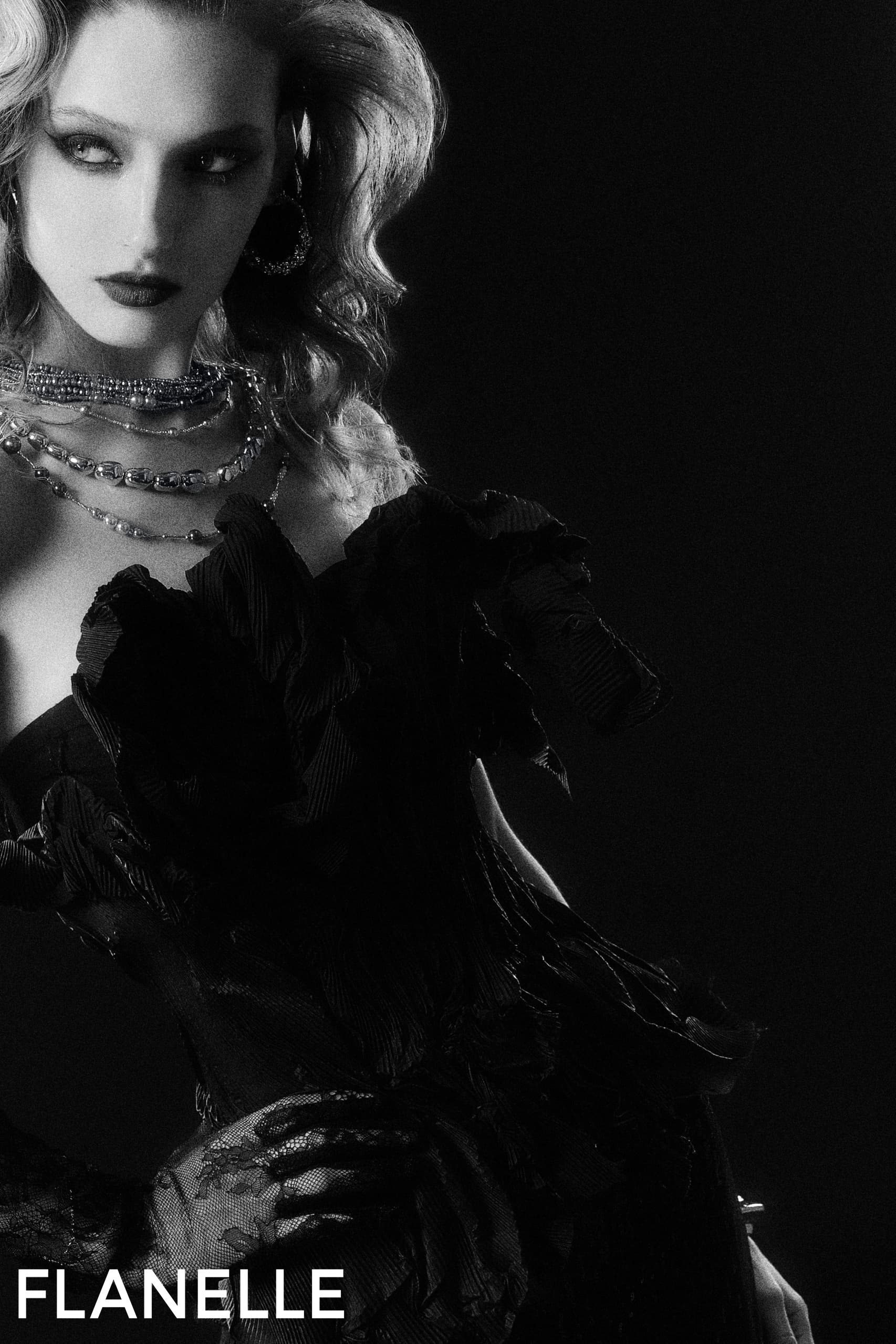 Black and white fashion portrait in elegant vintage attire with layered necklaces.