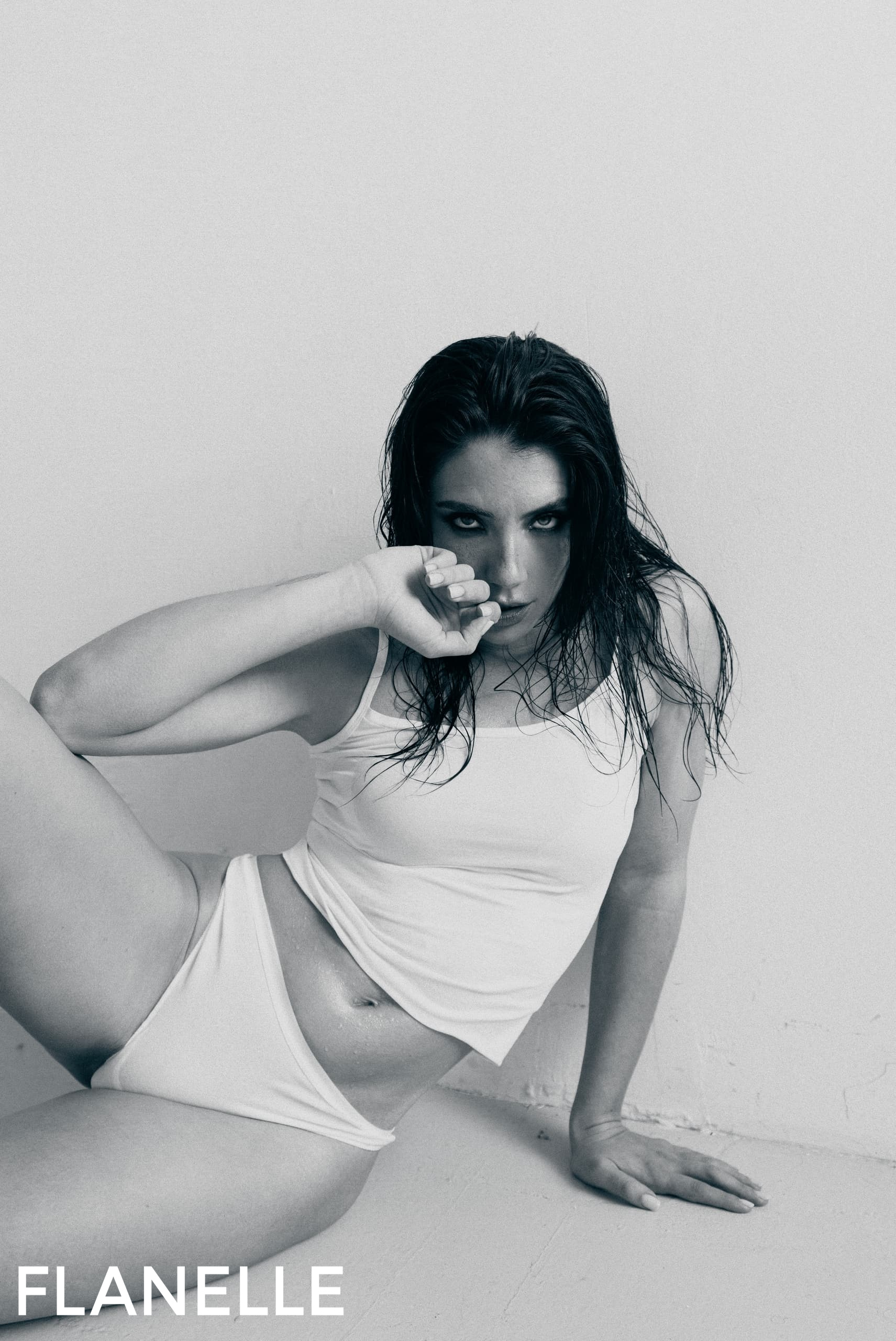 Fashion model poses in stylish monochrome outfit against a minimalist backdrop.