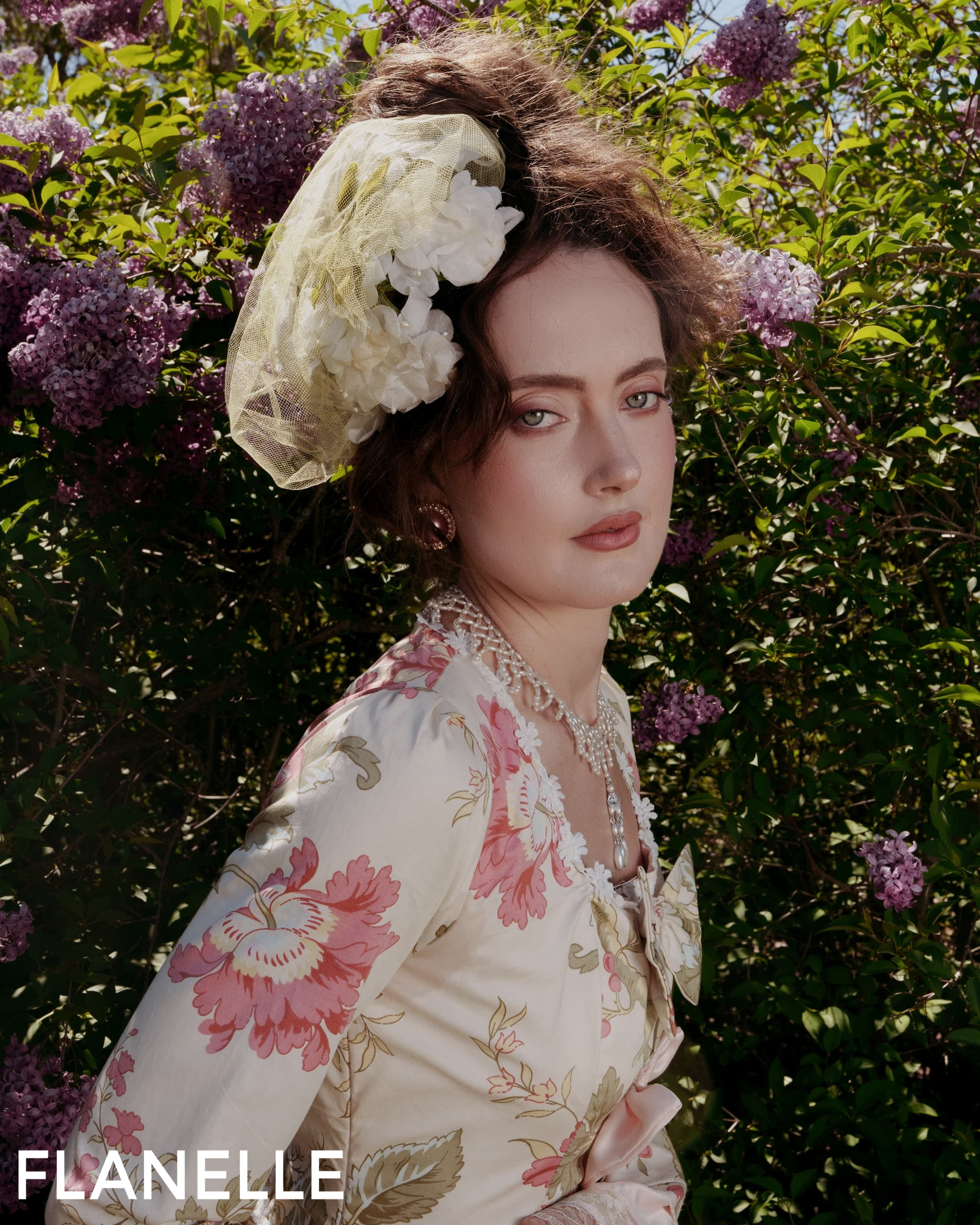 Elegantly dressed woman with floral accessories in a garden setting.