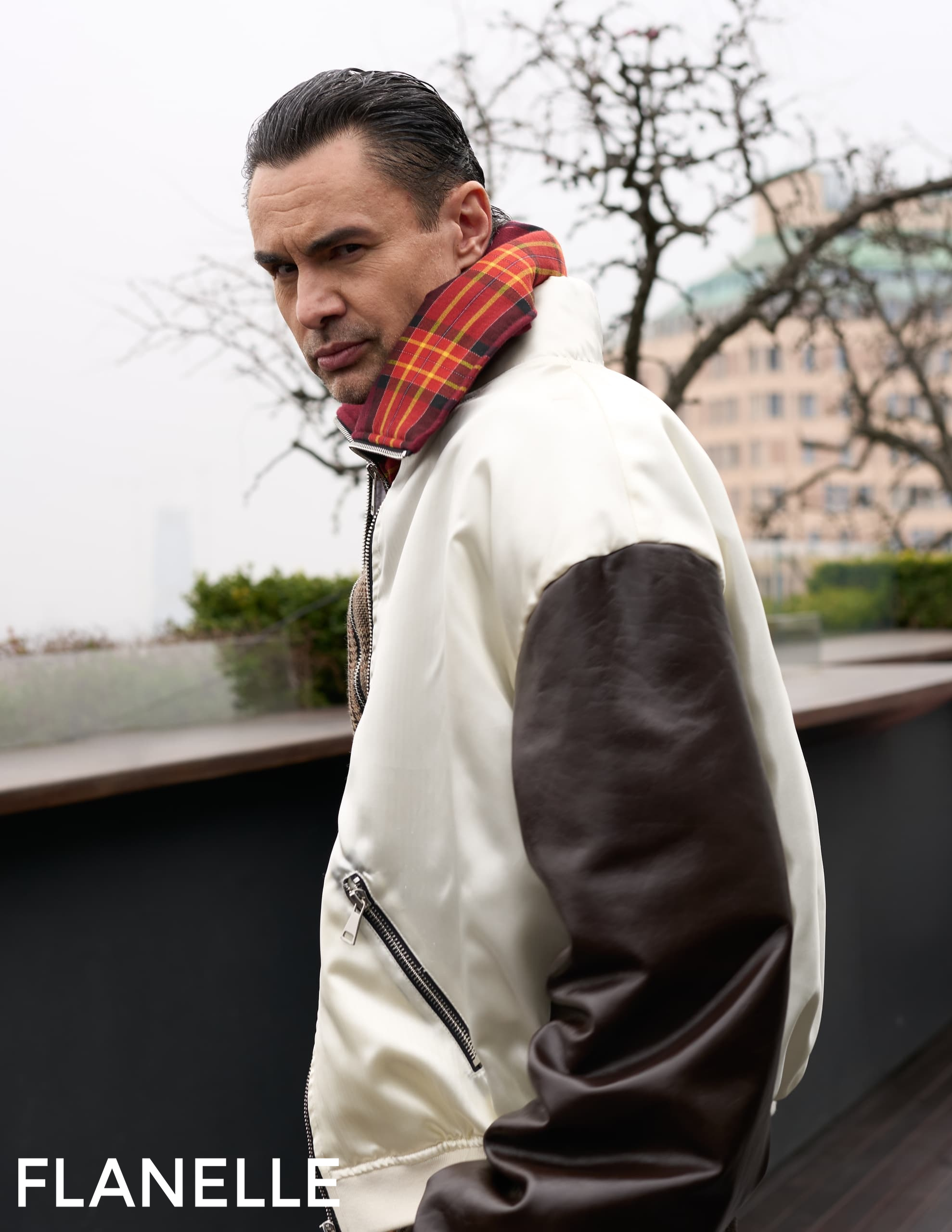 Man in stylish jacket with red plaid collar outdoors.