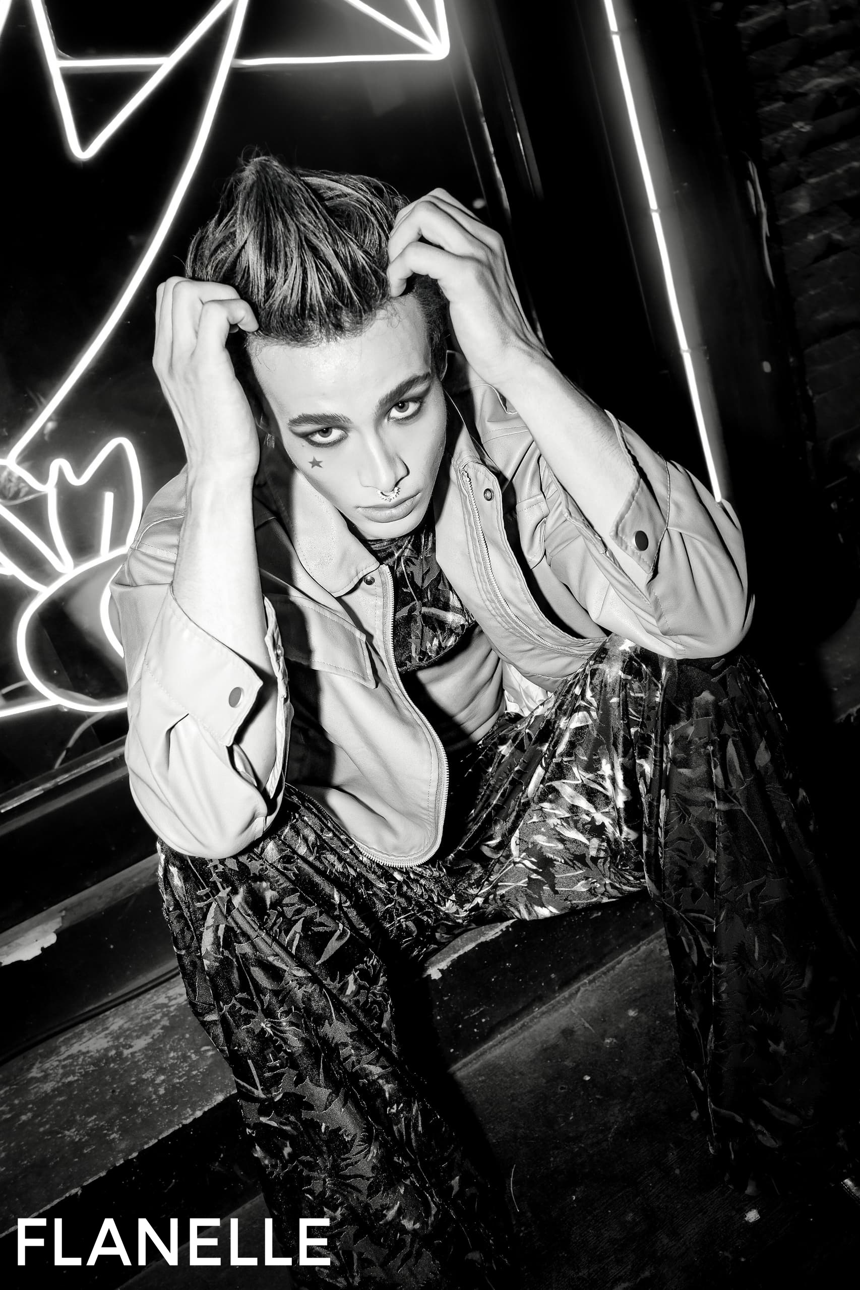 Fashionable person in bold makeup posing for edgy black and white photo shoot.