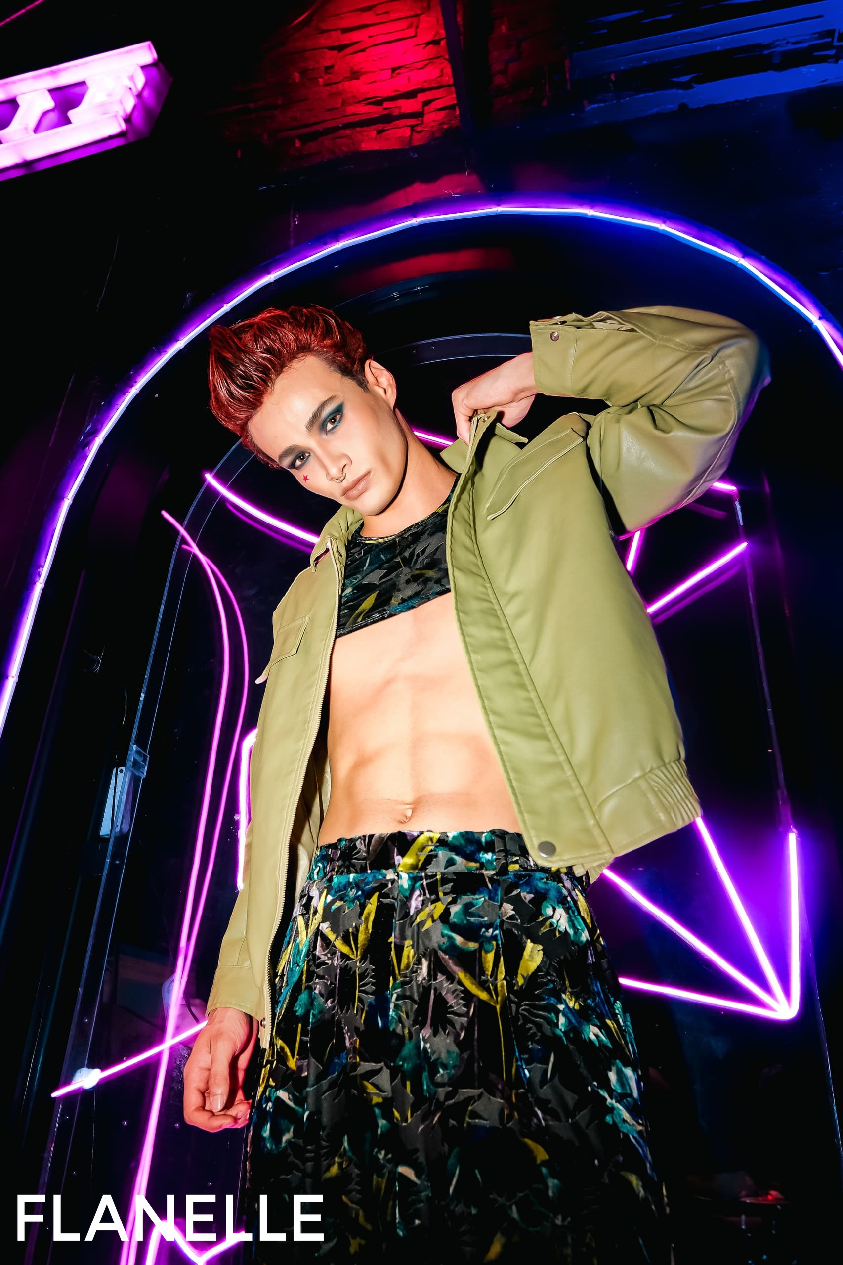 Fashion model in bold outfit under vibrant neon lights.