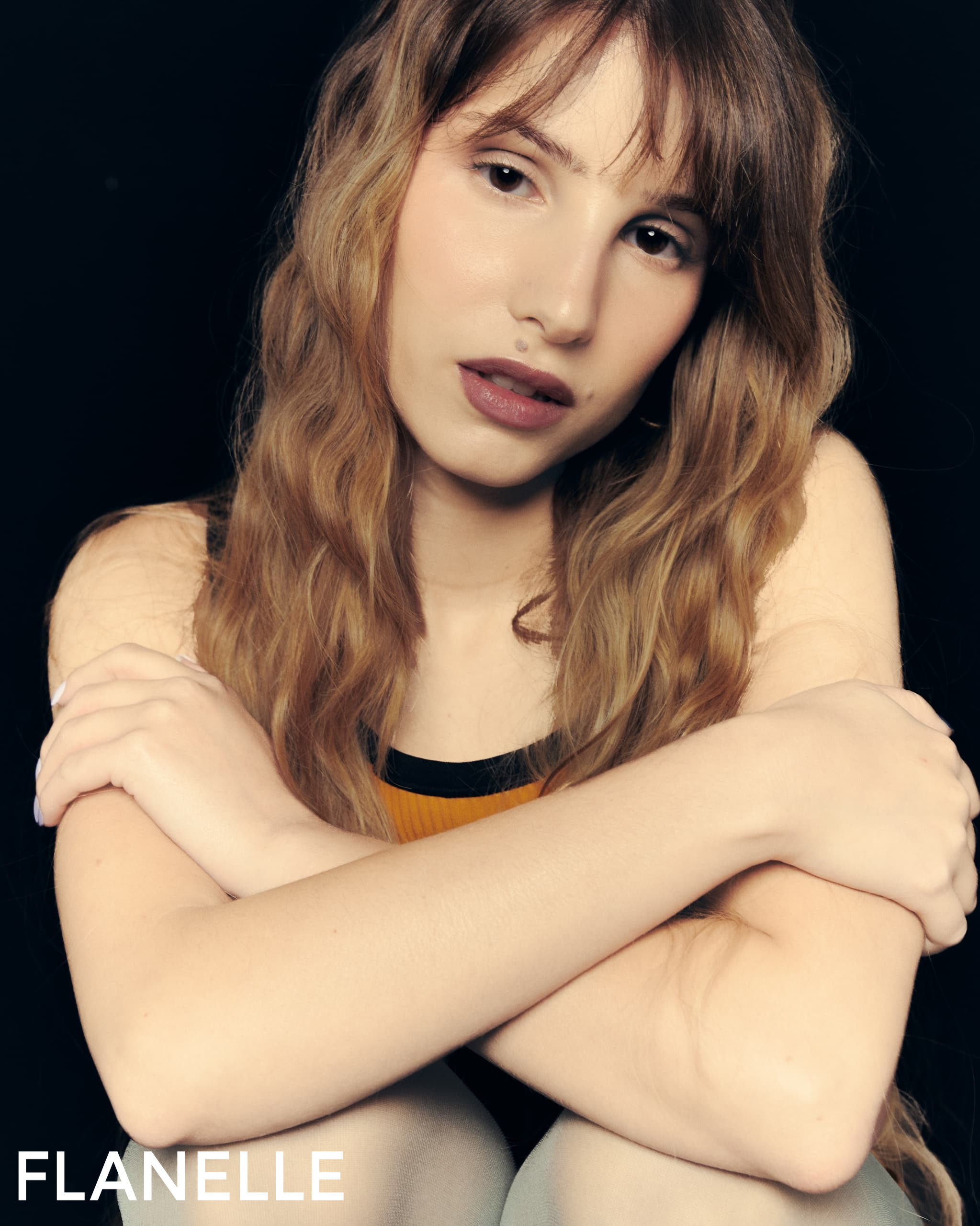 Portrait of a woman with long hair, seated against a dark background.