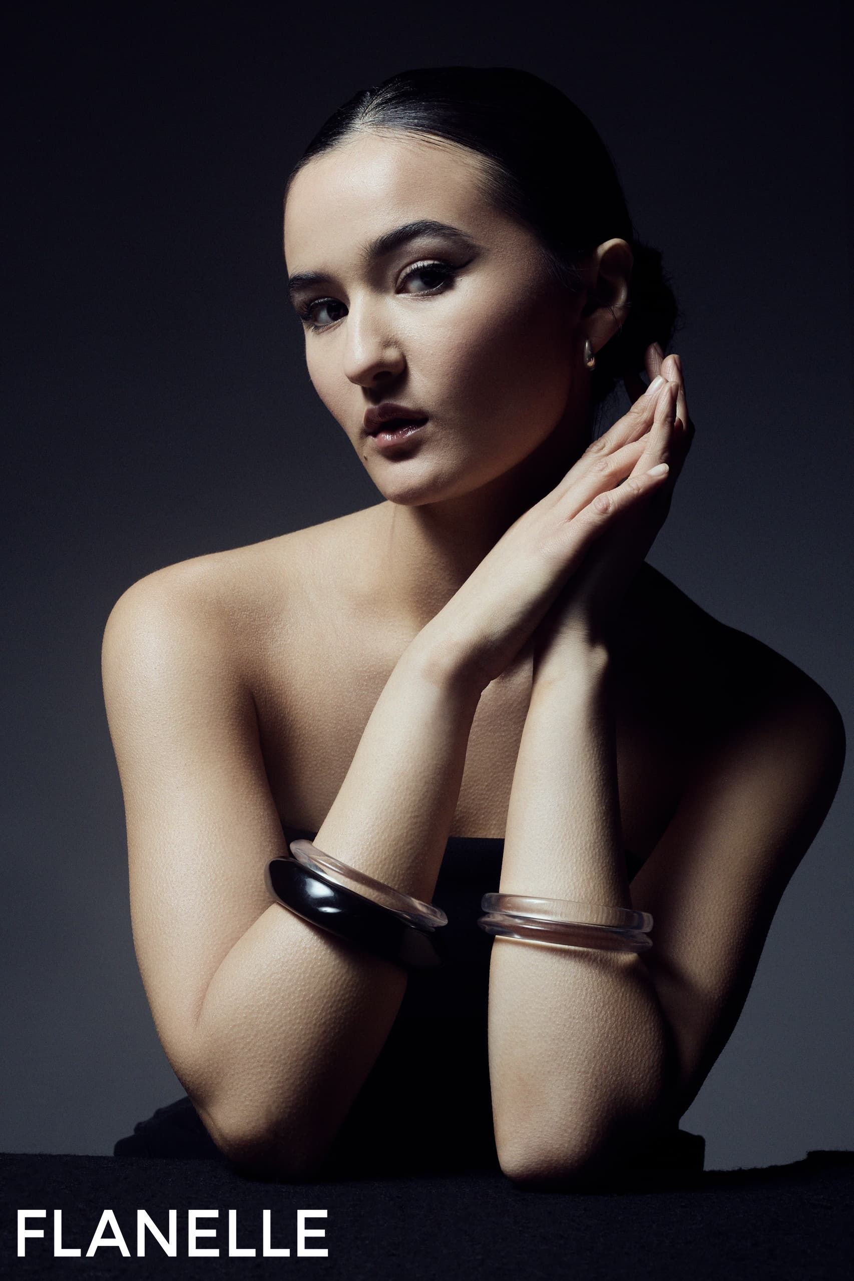 Elegant woman in dark attire posing with stylish bangles, Flanelle magazine cover.