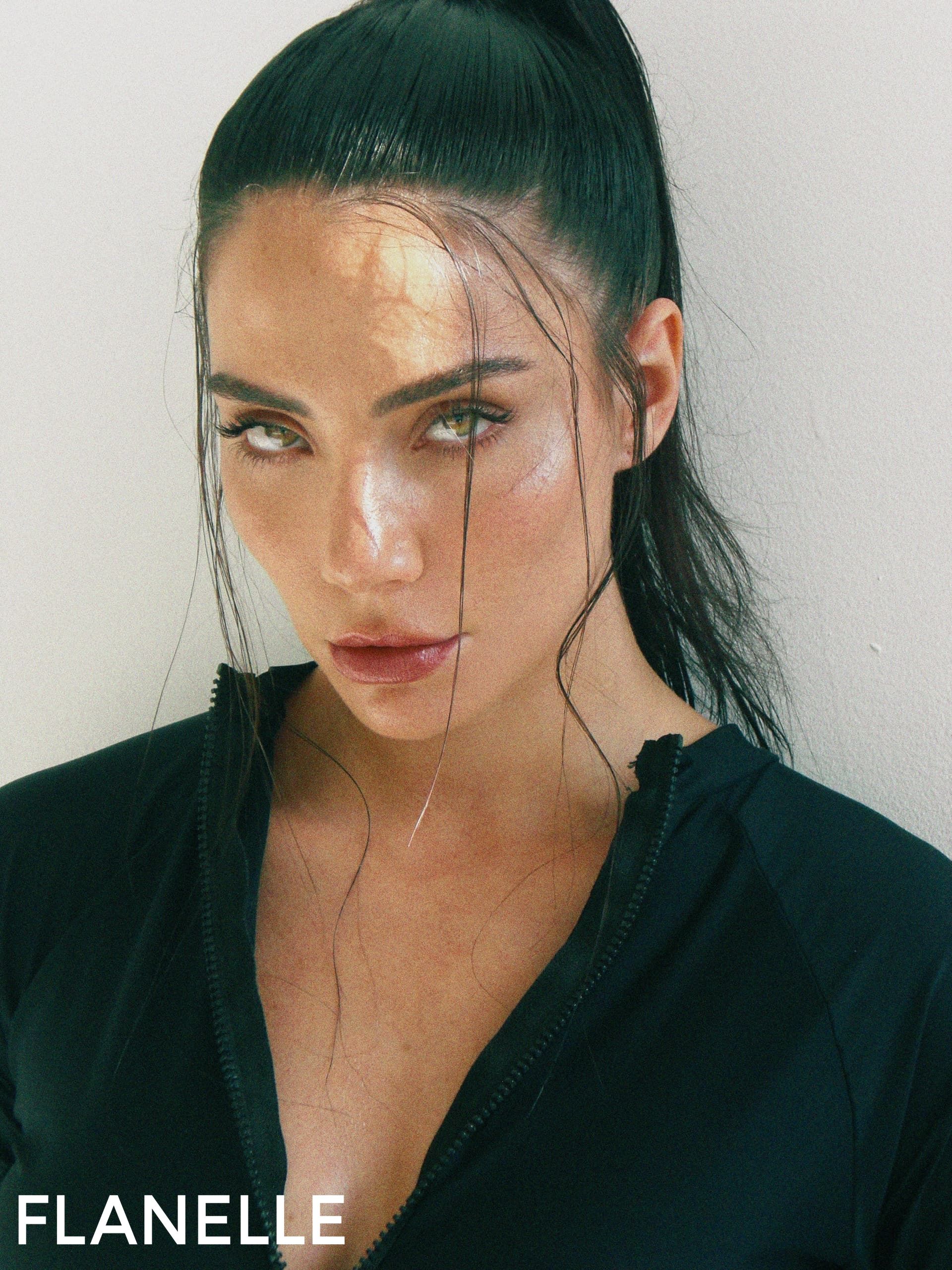 Portrait of a woman in a black outfit with sleek hair and intense gaze.