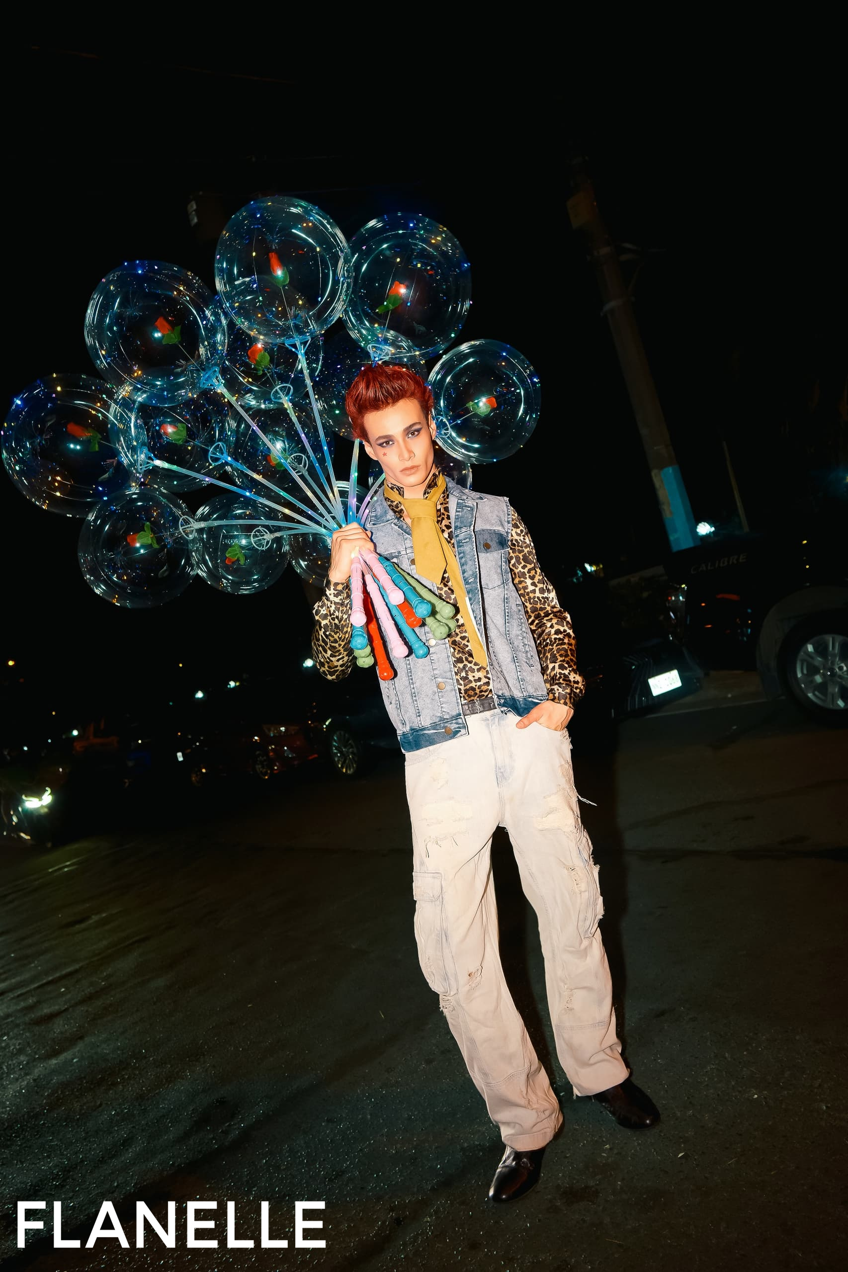 Person in stylish outfit holding balloons at night.